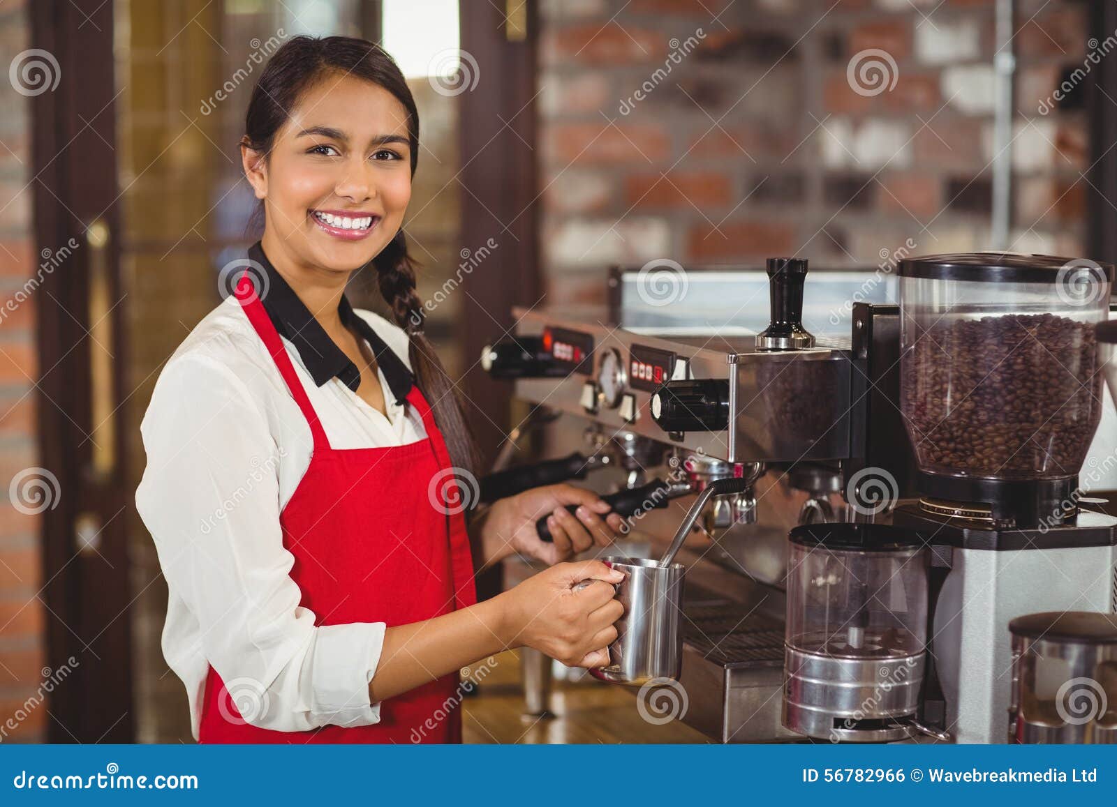 smiling barista steaming milk at the coffee machine