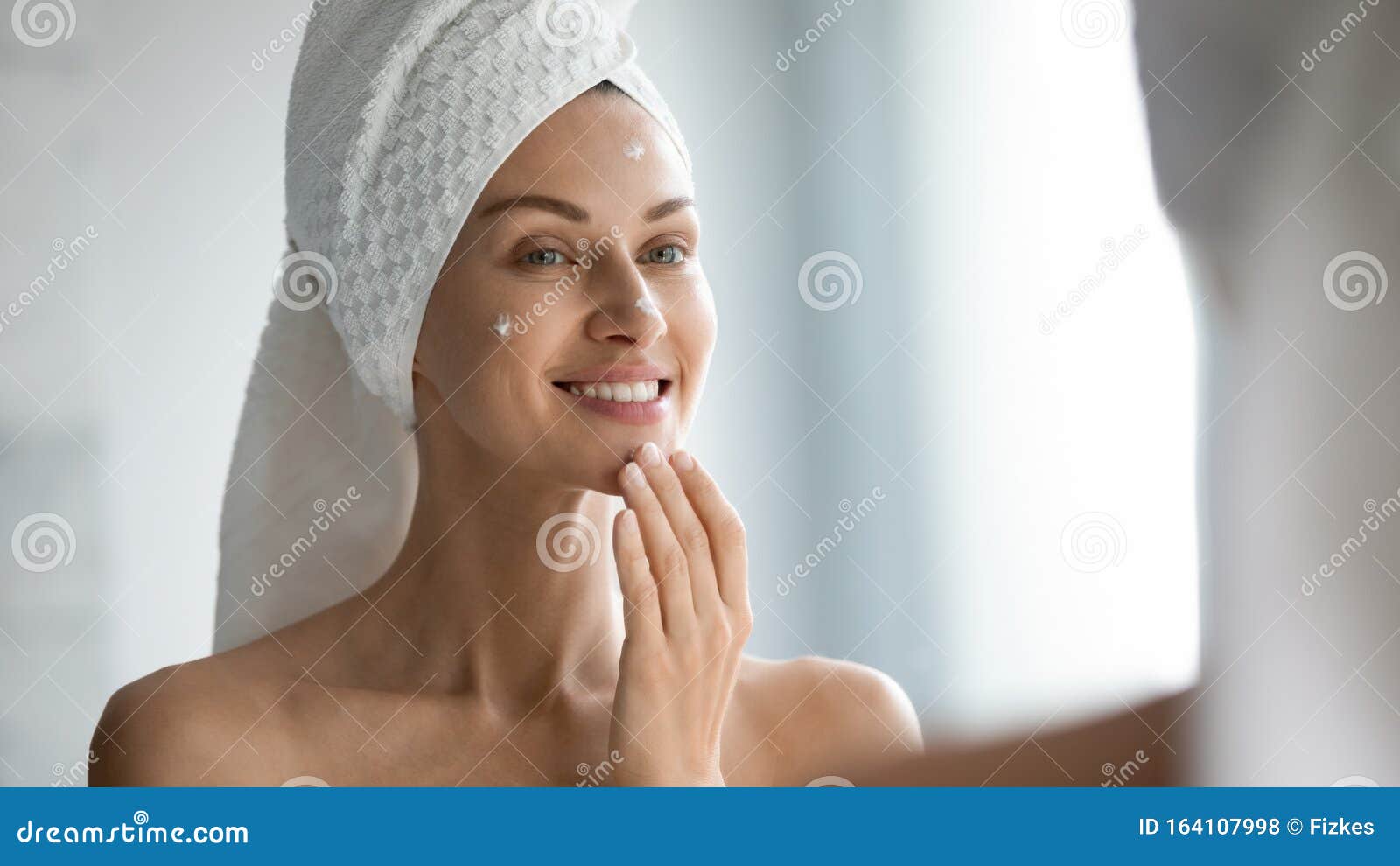 smiling beautiful lady apply skincare cream look in mirror