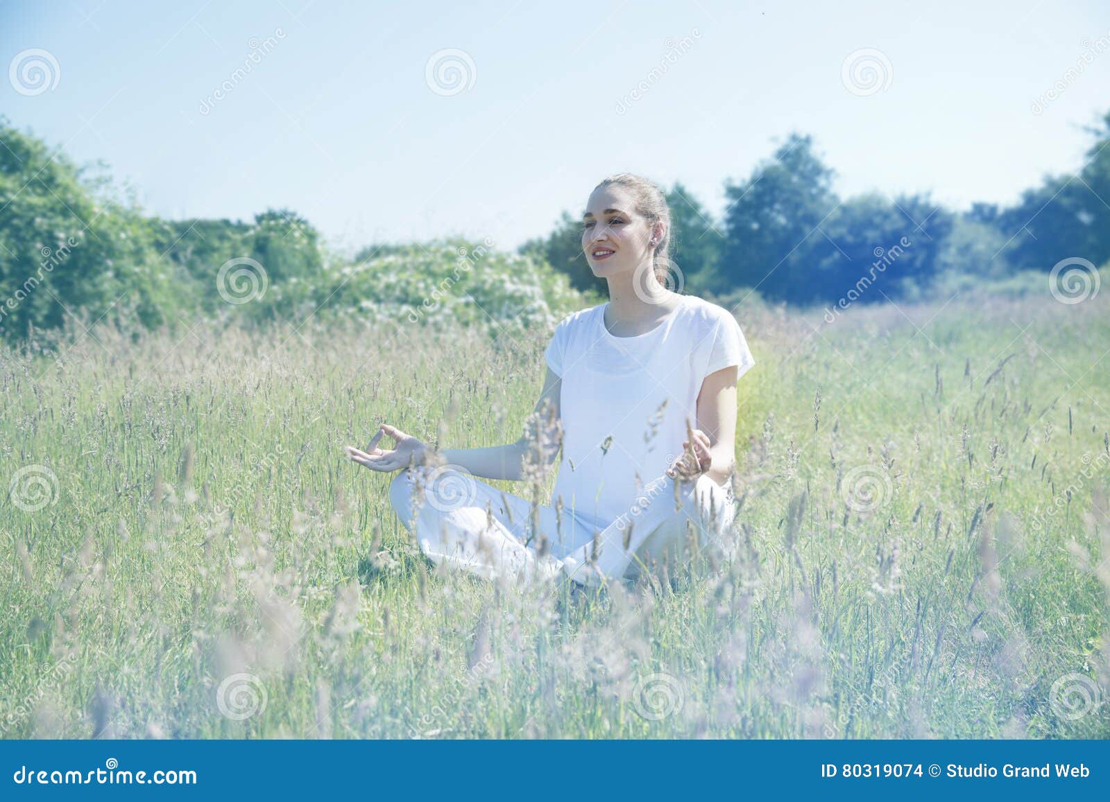 smiling beautiful yoga girl meditating for openness in green environment