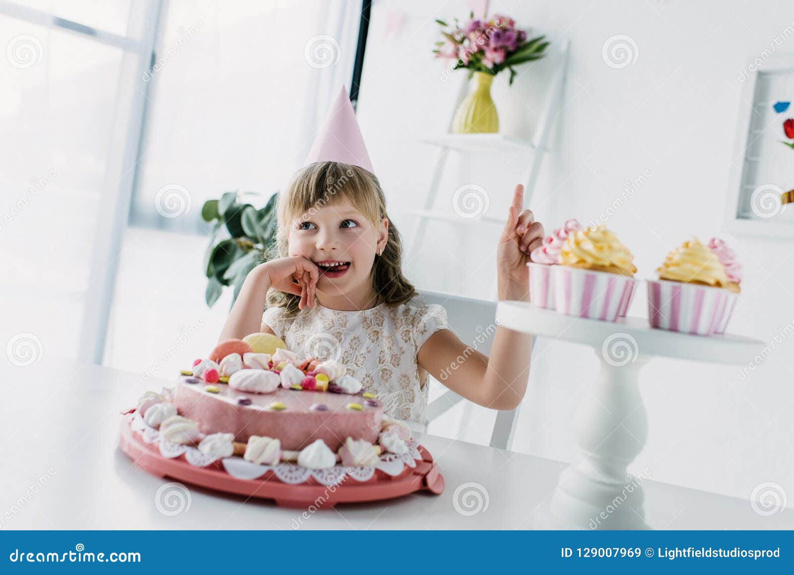 Smiling Birthday Kid in Cone Doing Idea Gesture while Sitting at Table ...