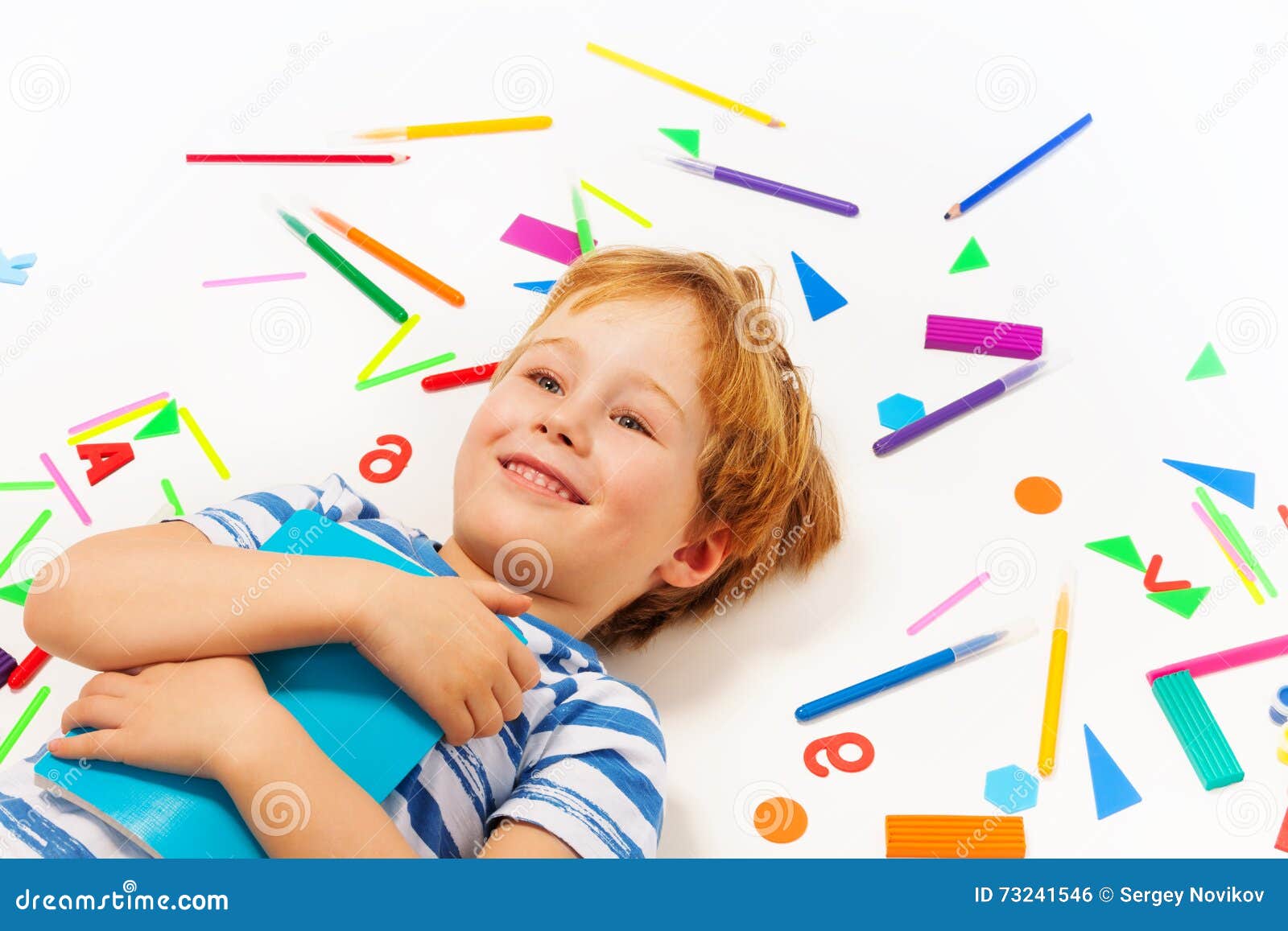 smiling boy having a rest among heap of stationery