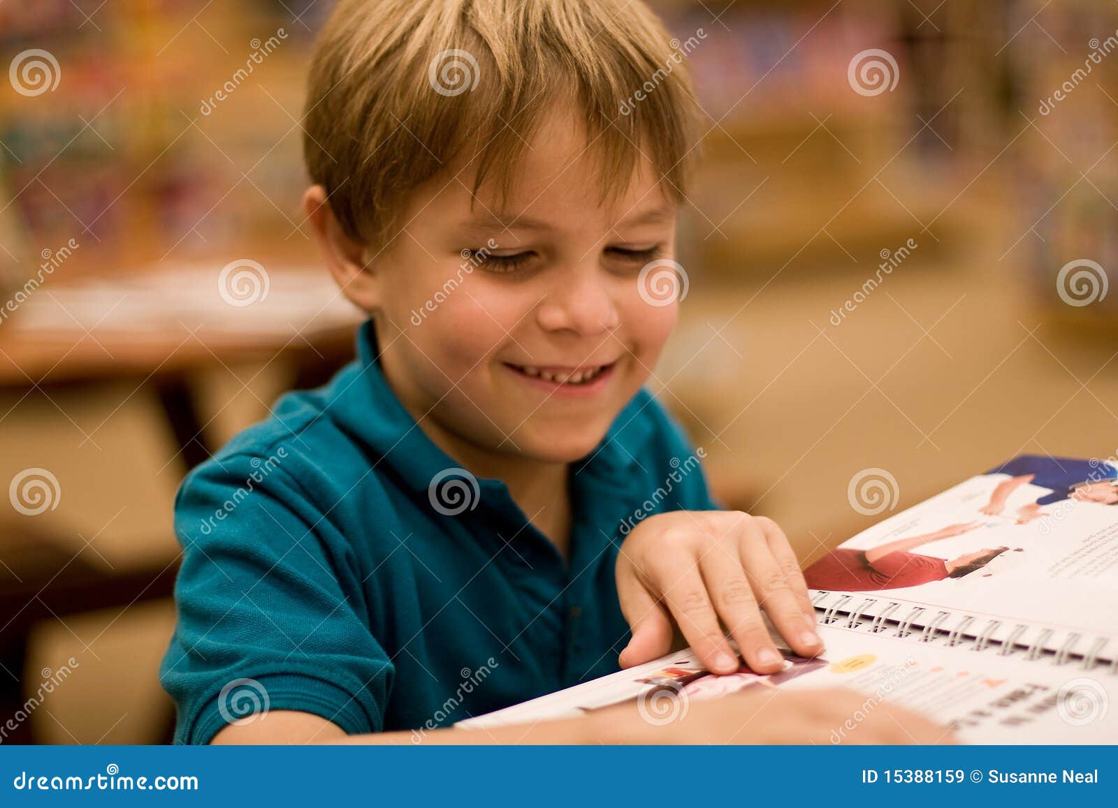 smiling boy reads a book at libary