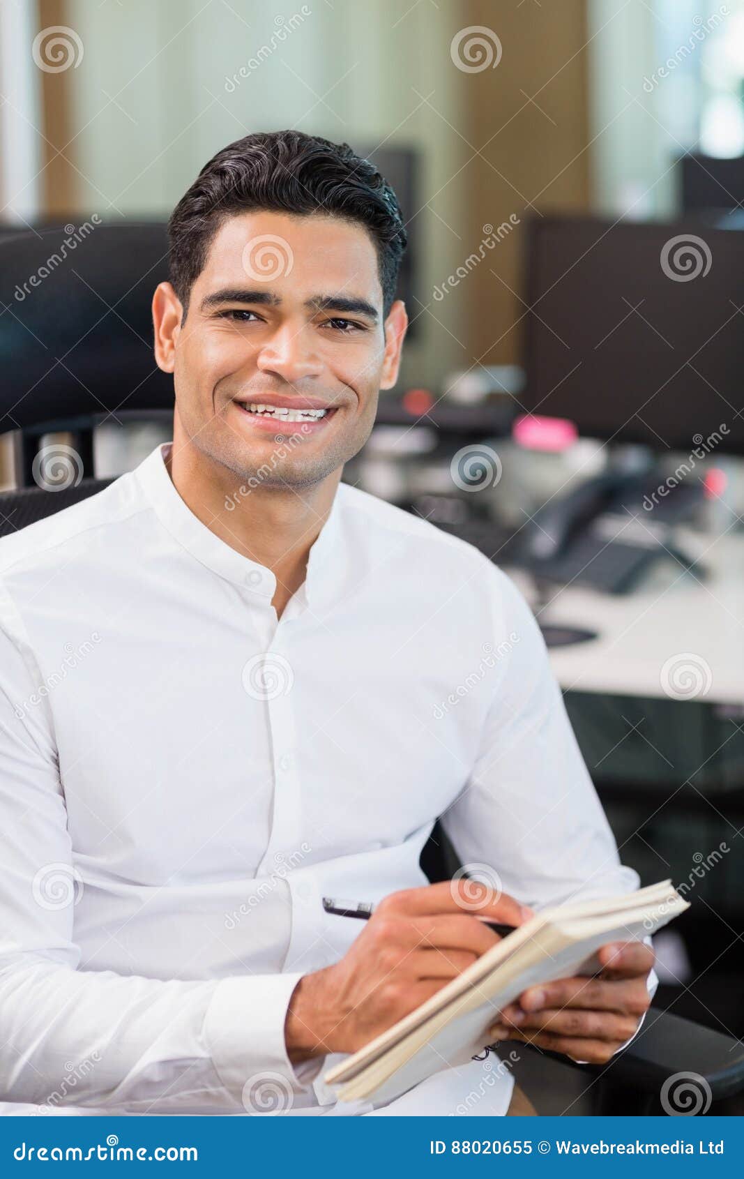 Smiling Business Executive Writing on Notebook in Office Stock Image
