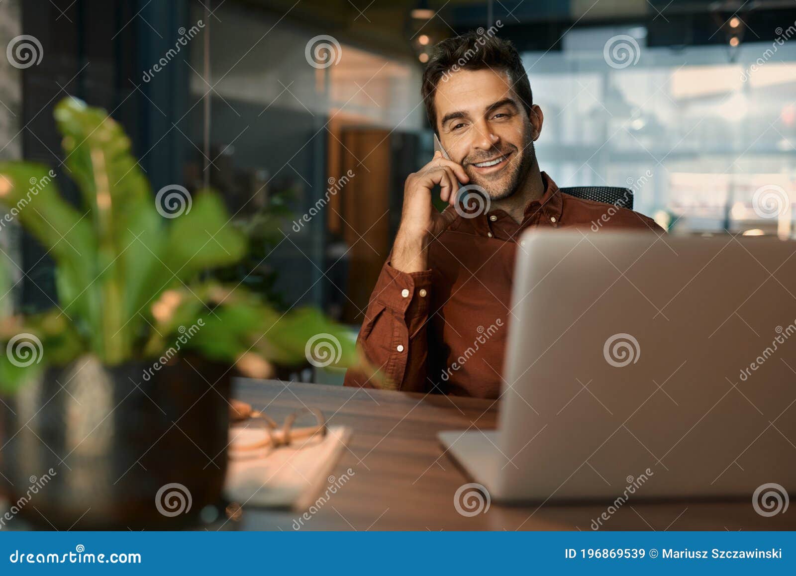smiling businessman talking on a cellphone while working late