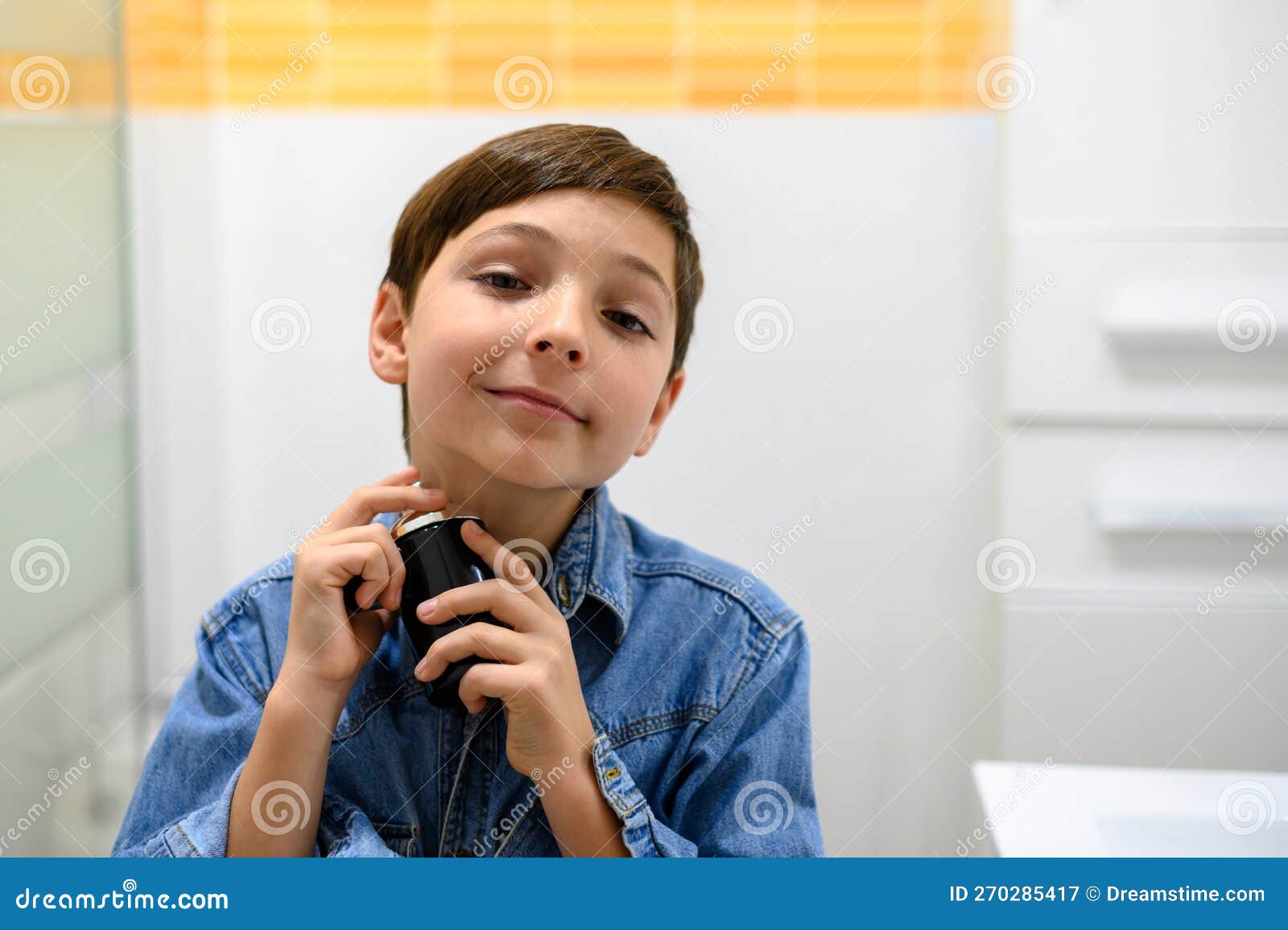 Smiling Child Sprays Cologne on His Neck while Looking at the Camera
