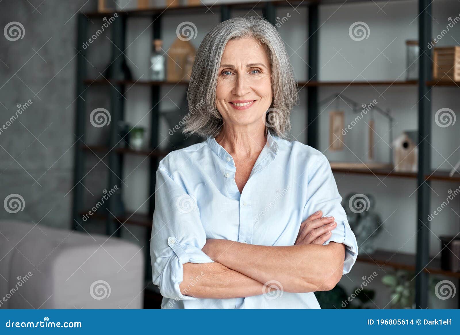 smiling confident middle aged woman standing arms crossed in office, portrait.