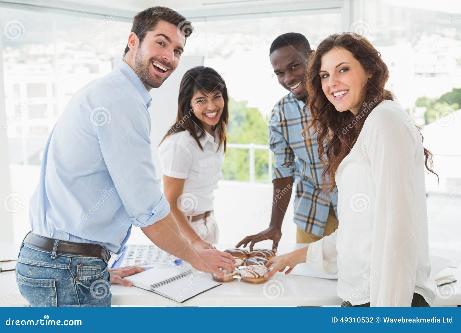 smiling coworkers taking doughnut at desk