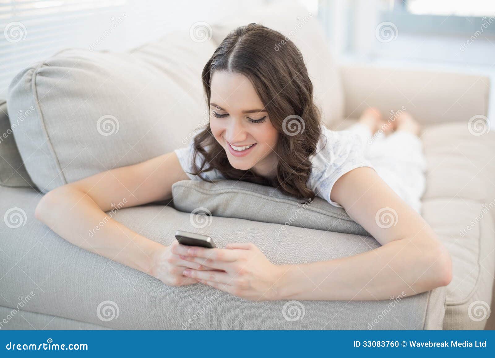 Smiling Cute Woman Lying on a Cosy Couch Sending Text Message Stock ...