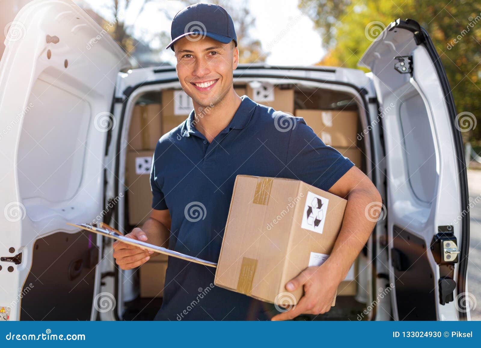 smiling delivery man loading boxes into his truck