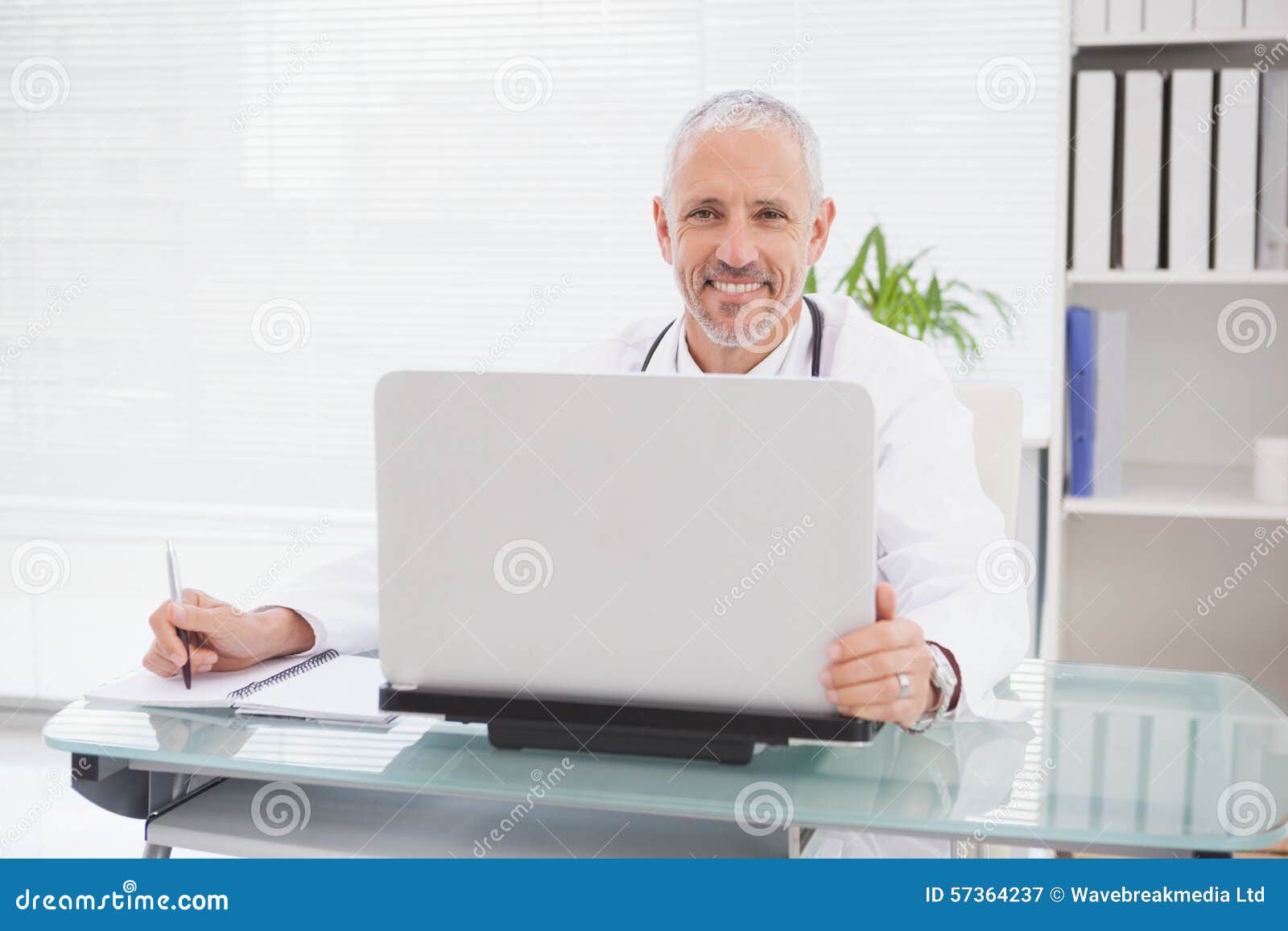 Smiling Doctor Using Laptop and Writing Stock Image - Image of ...