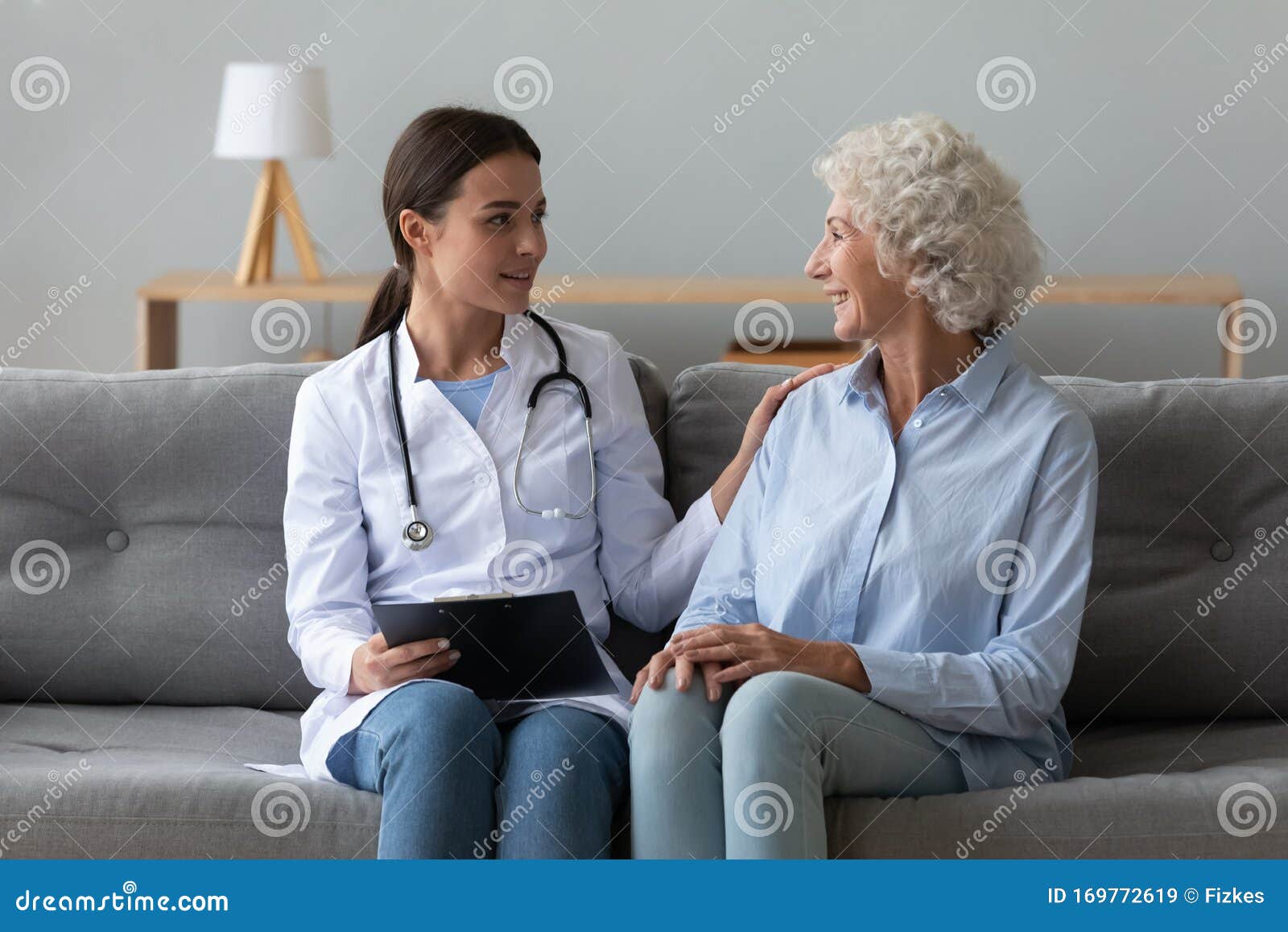 smiling doctor consulting older woman patient during visit at home