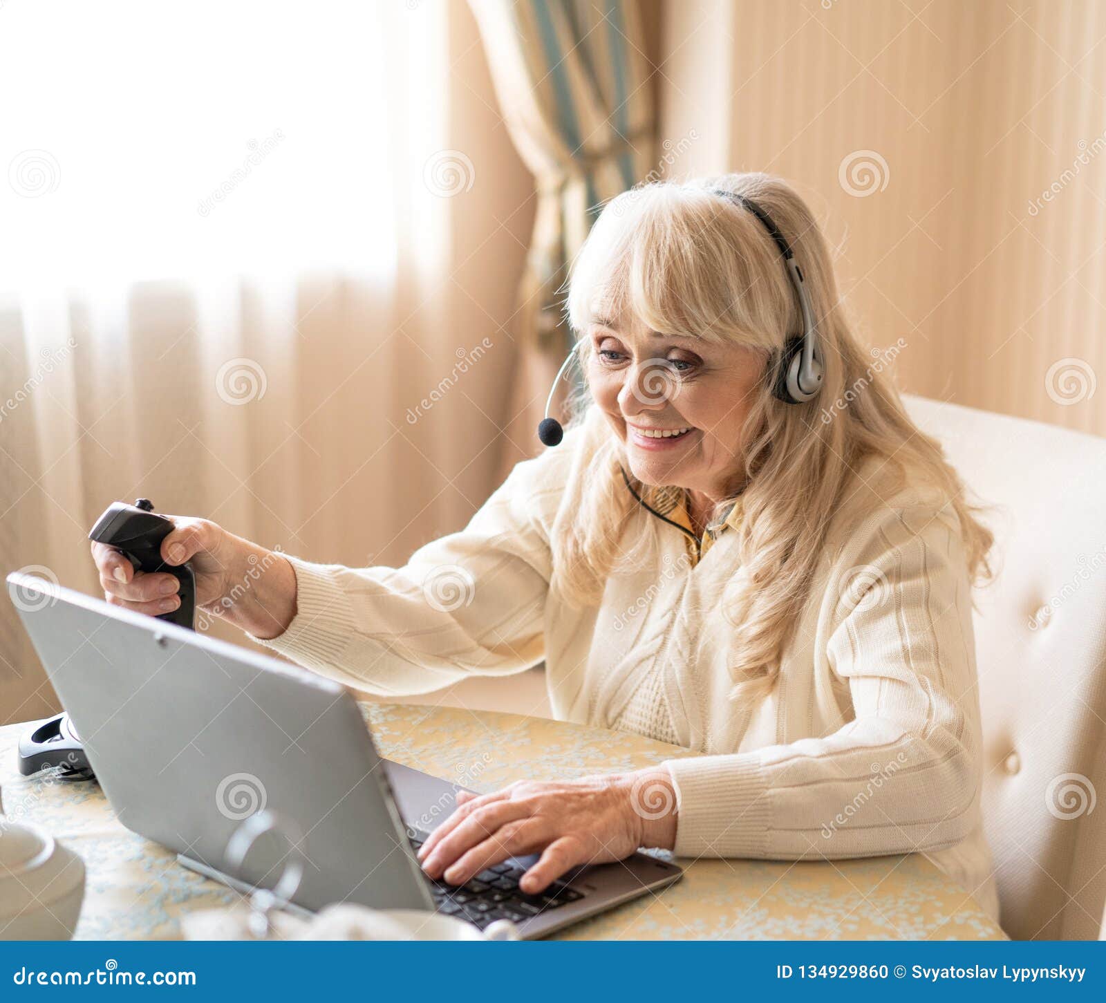 Senior Woman Plays Video Games with Joystick on a Laptop Stock Photo ...