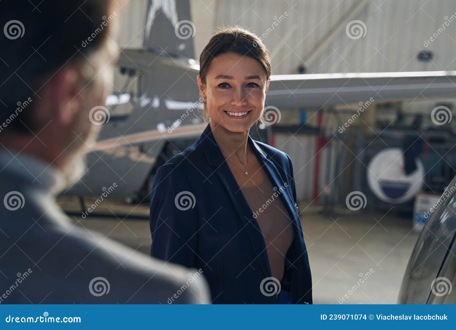joyful lady standing before man in aircraft hangar