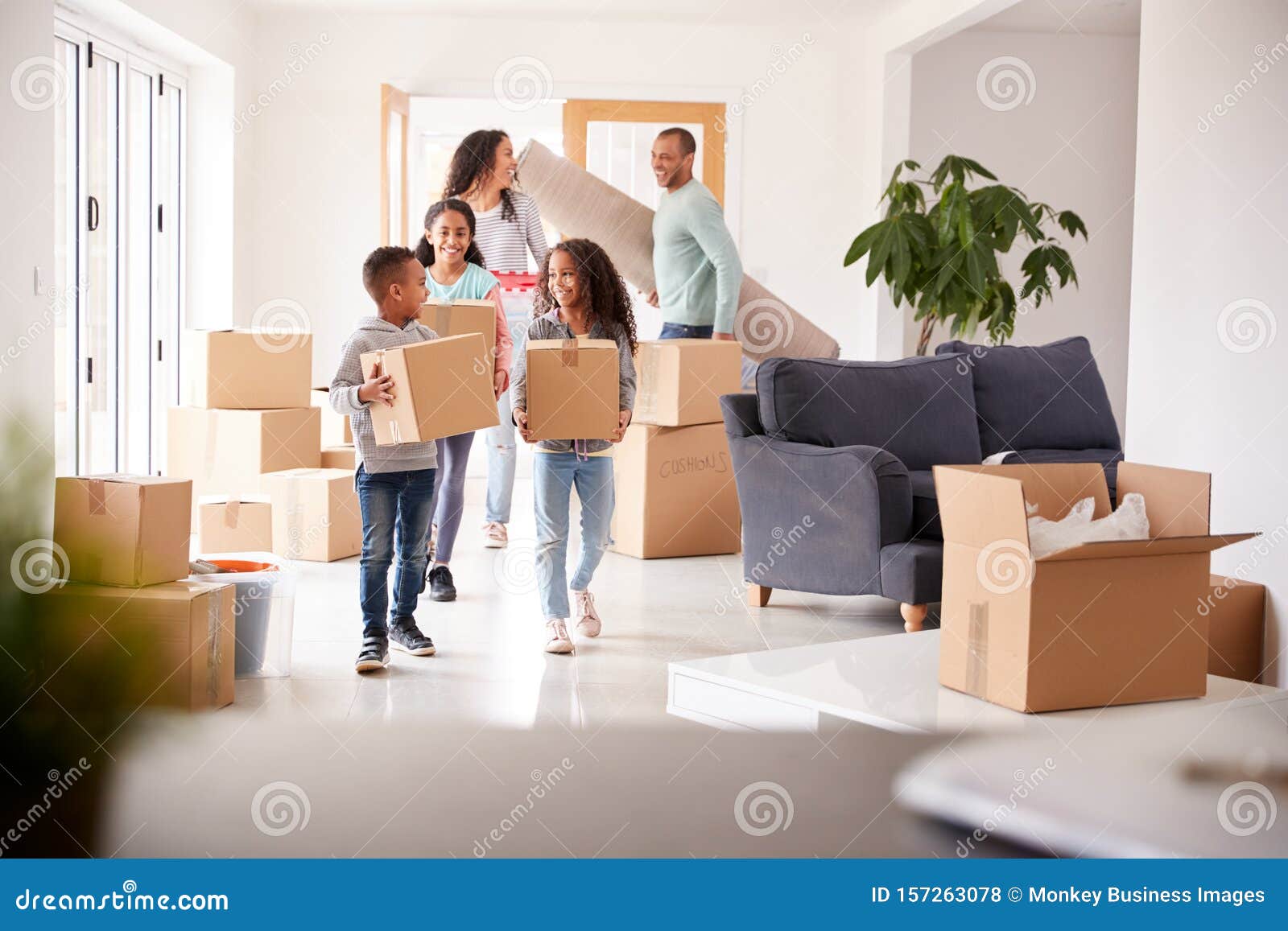 smiling family carrying boxes into new home on moving day