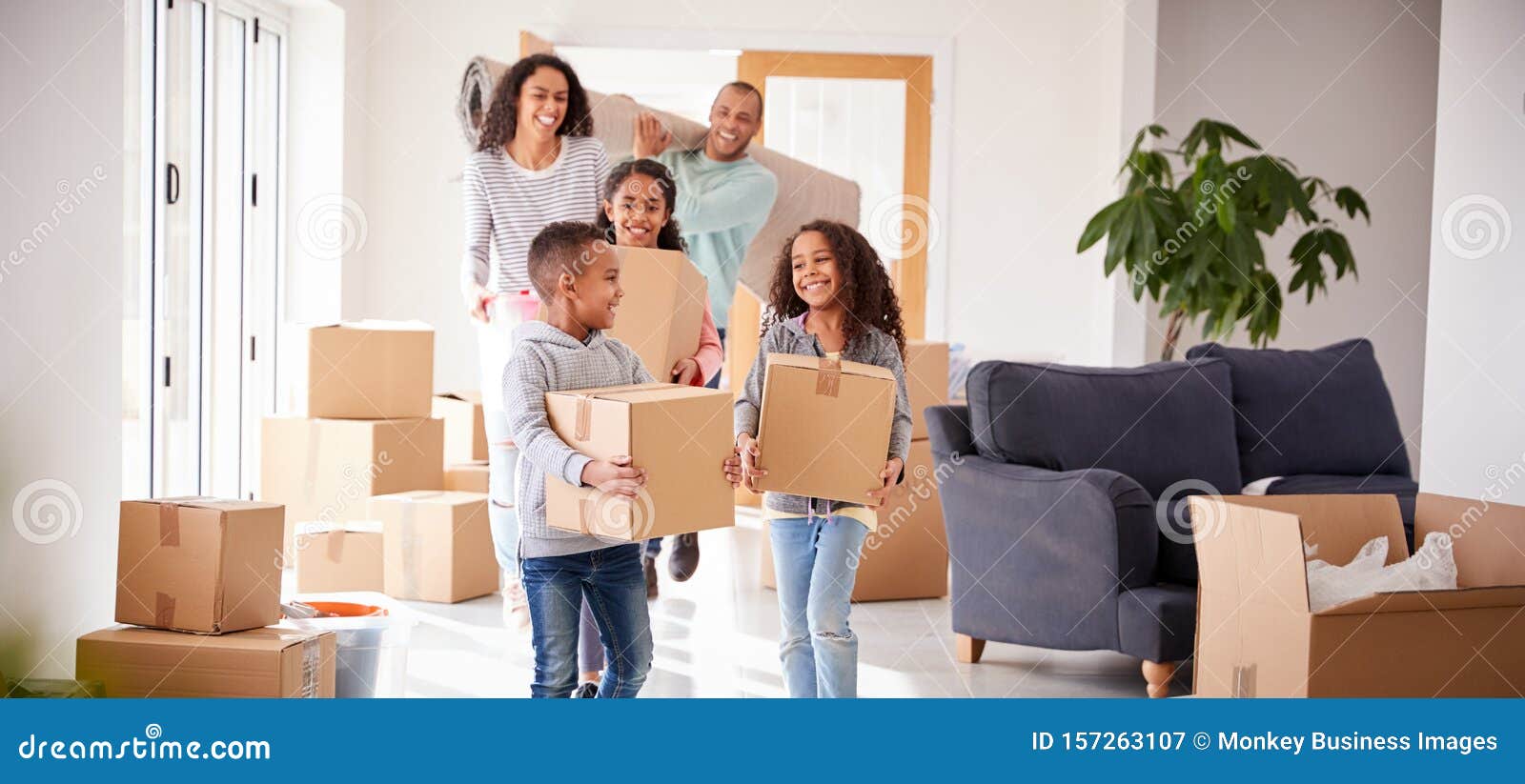 smiling family carrying boxes into new home on moving day