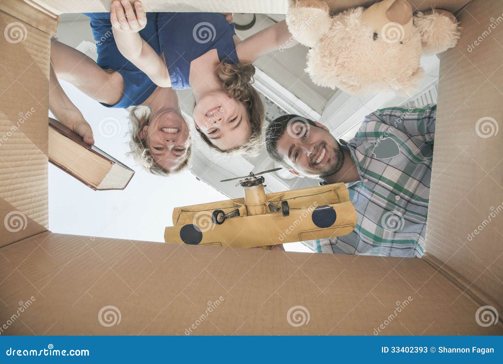 smiling family looking into a cardboard box, view from directly under