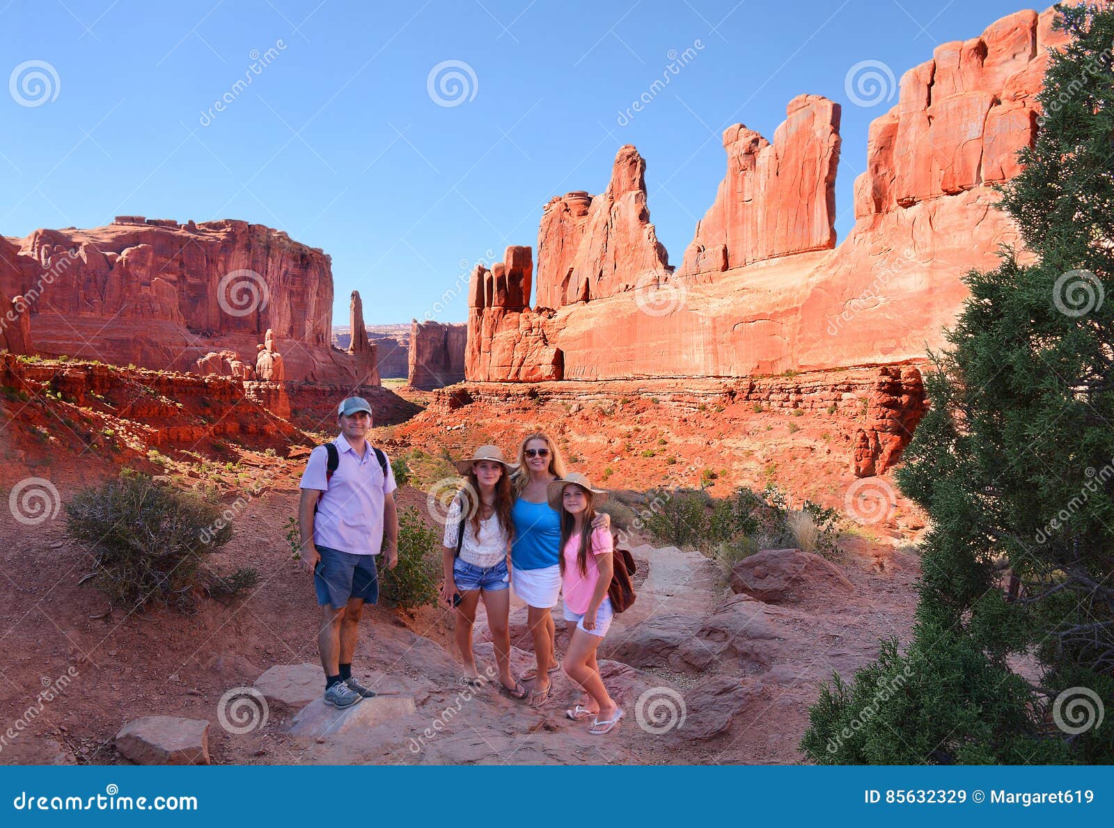 Smiling family on sightseeing trip in mountains. Family on sightseeing trip. Smiling, happy mother, father with daughters relaxing on vacation trip. Beautiful landscape made of red rocks. .Fifth Avenue, Arches National Park, Moab,Utah,USA