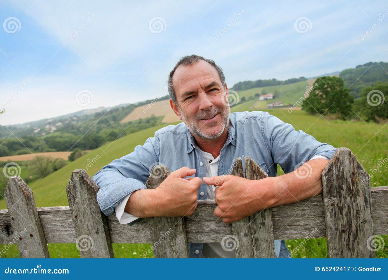 smiling farmer standing by fence