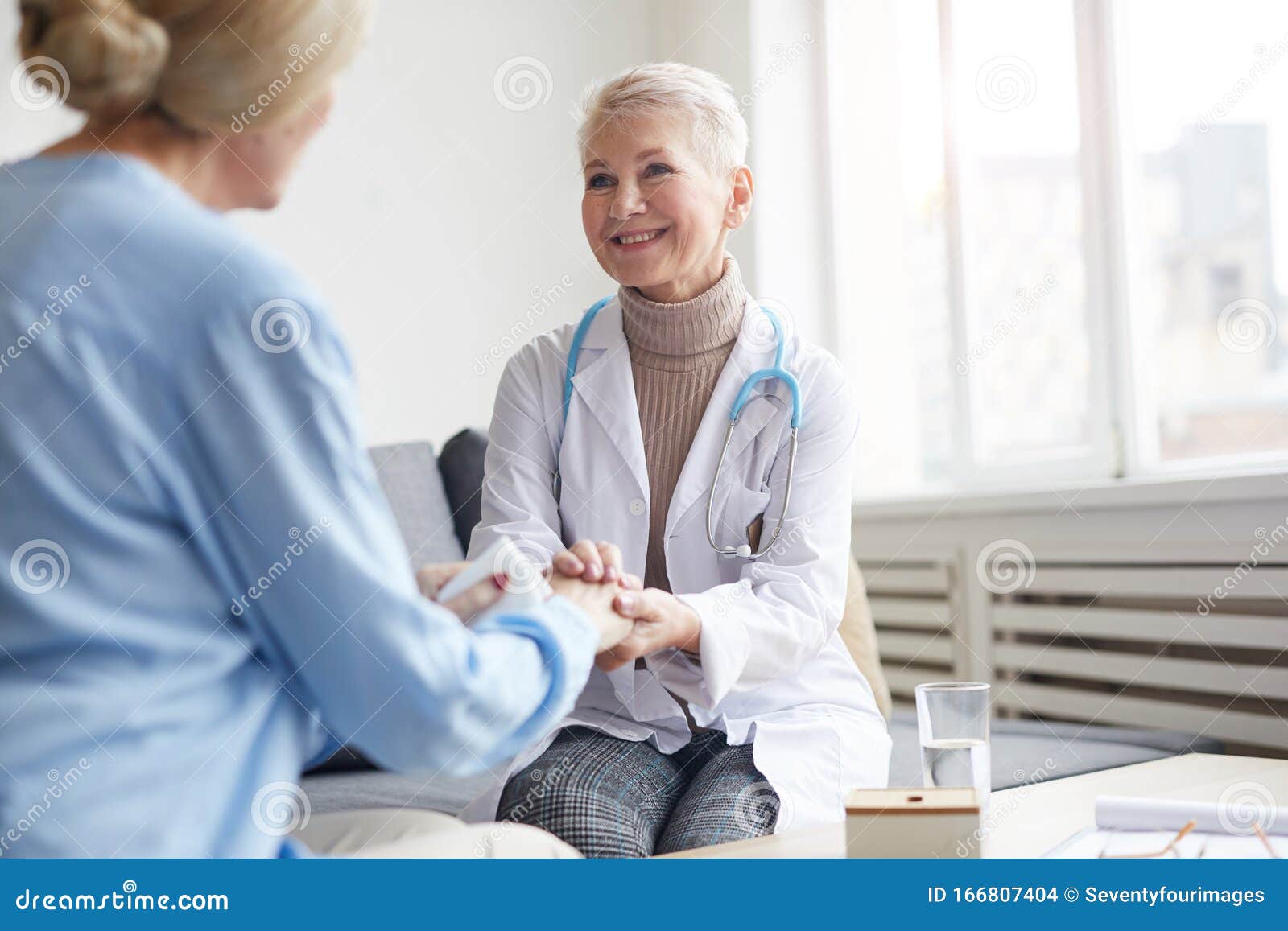 smiling female dostor holding hands with patient