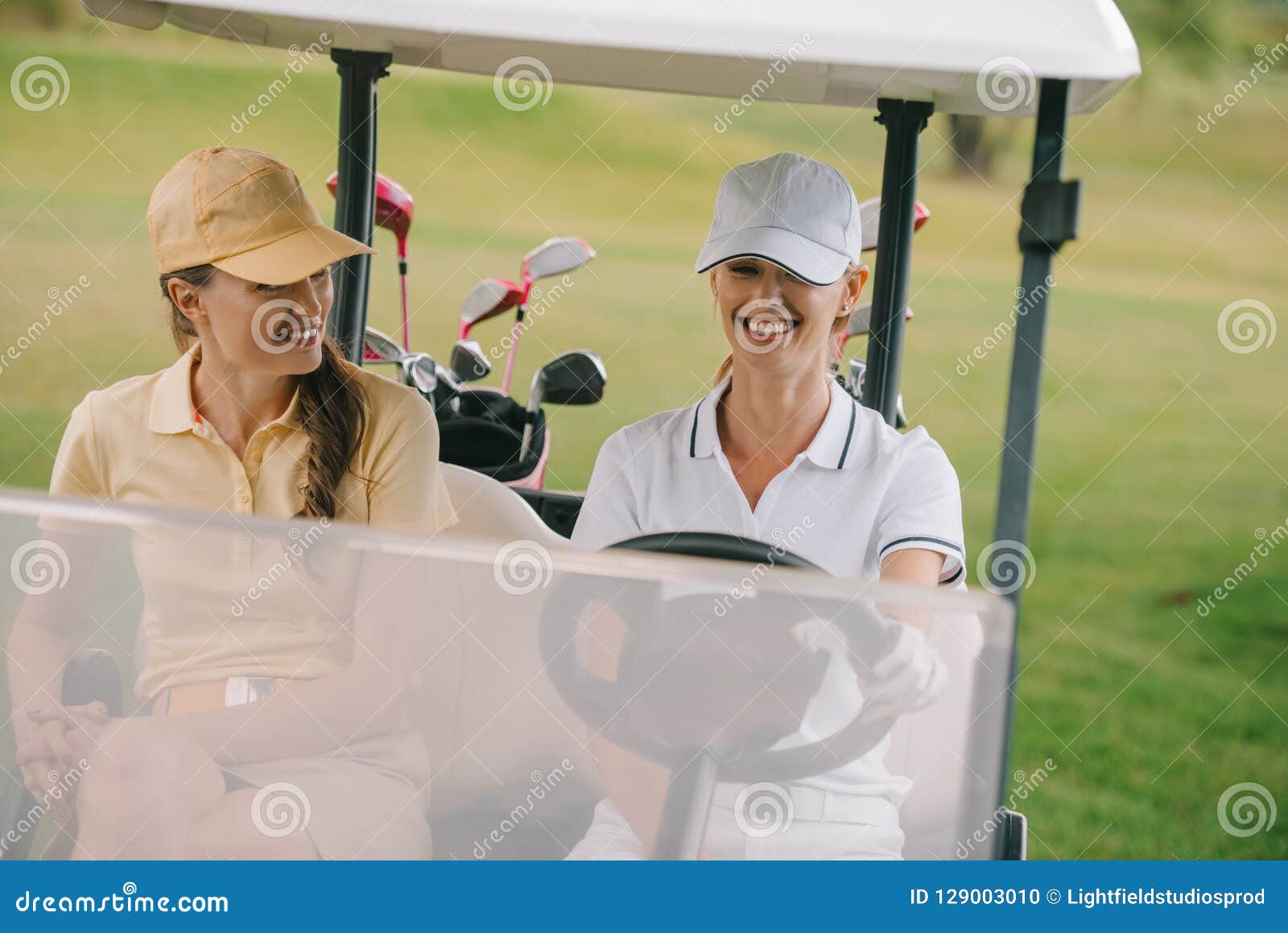 smiling female golf players riding golf cart