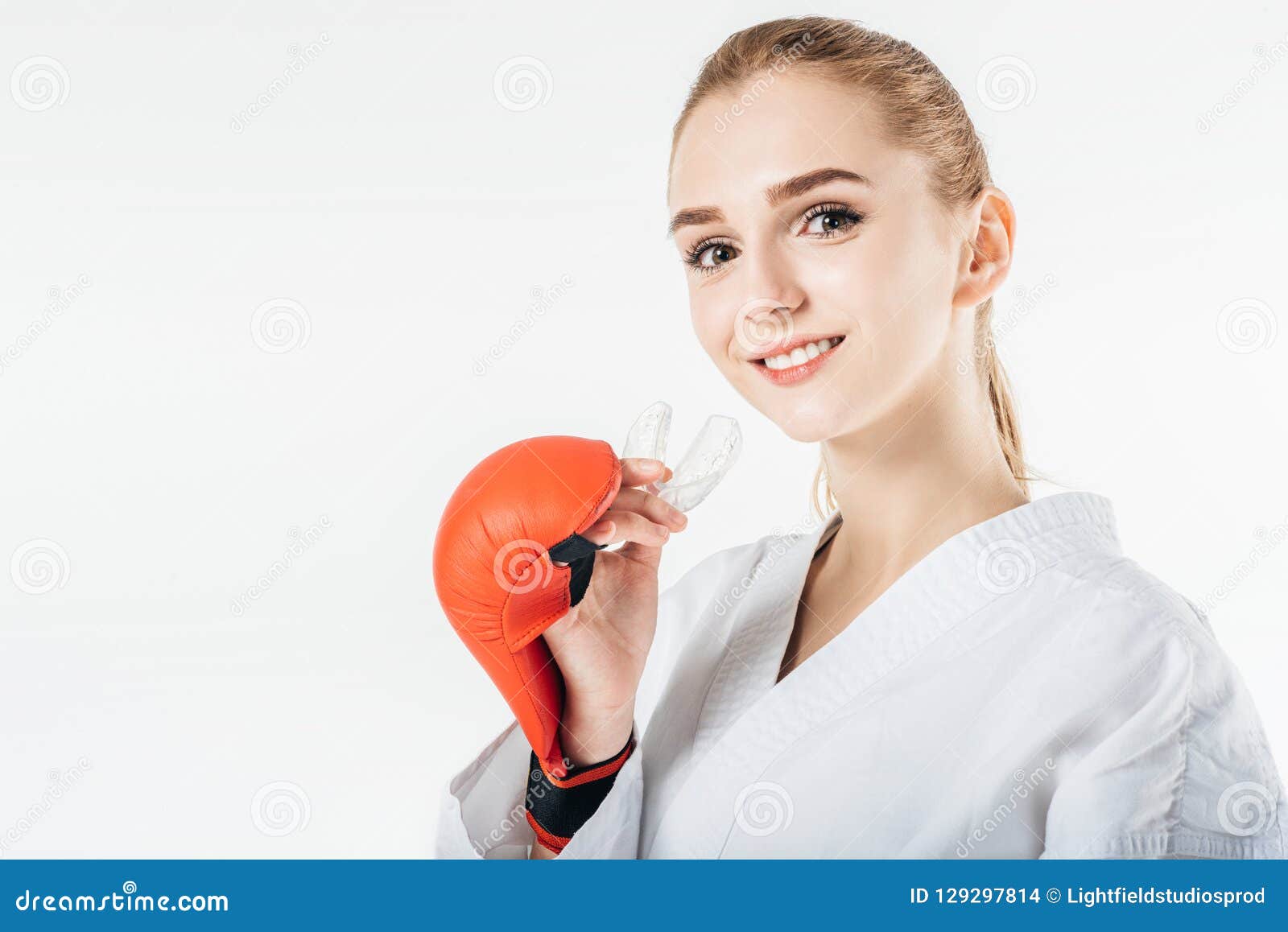 smiling female karate fighter holding mouthguard