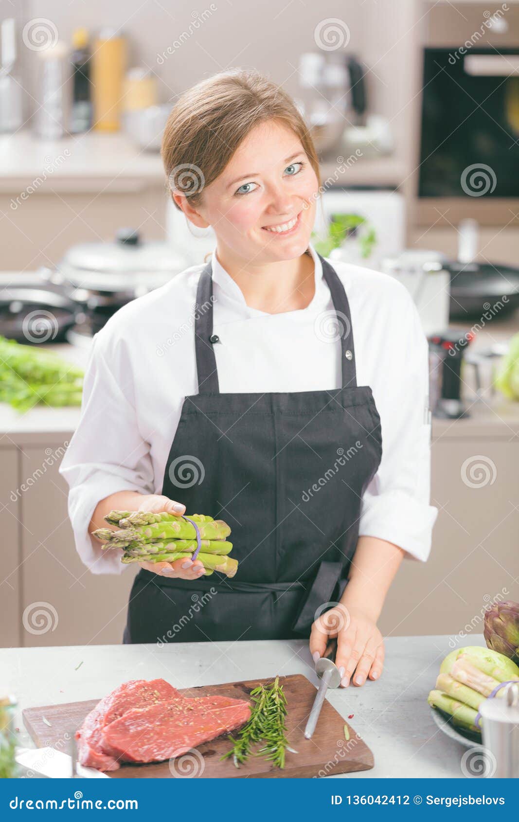 Smiling Female Kitchener in Uniform is Standing in the Kitchen at the