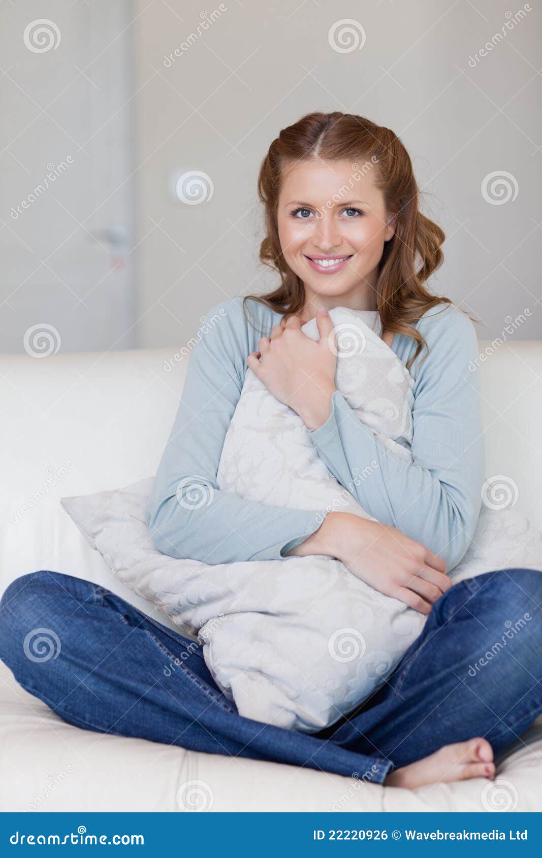 Smiling Female Sitting on the Sofa Hugging a Pillow Stock Photo Image