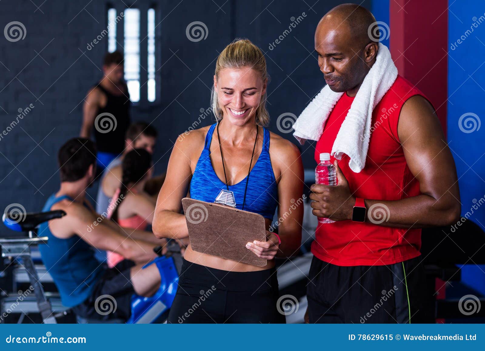 smiling fitness instructor discussing with man in gym