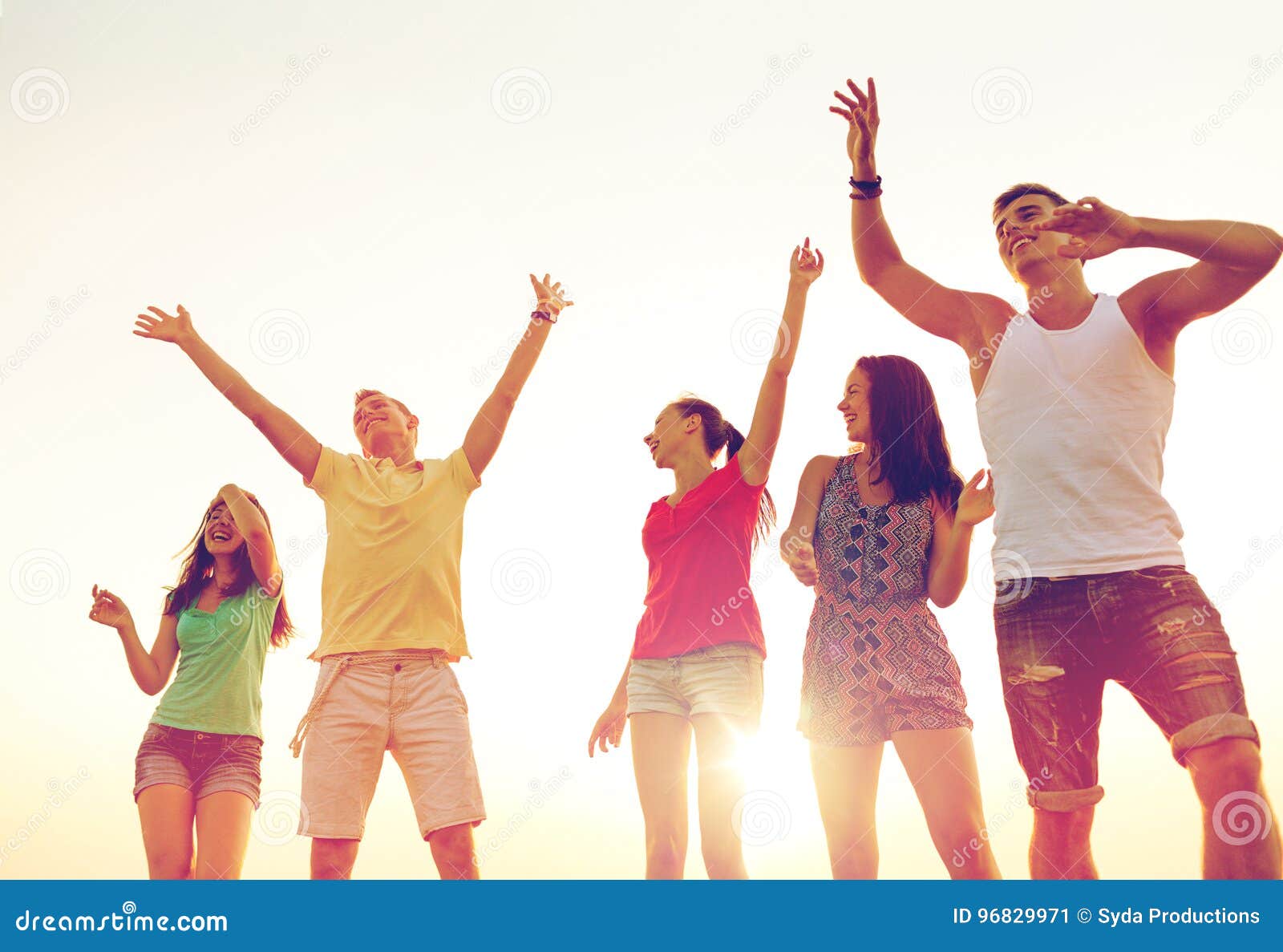 Smiling friends dancing on summer beach. Friendship, summer vacation, holidays, party and people concept - group of smiling friends dancing on beach