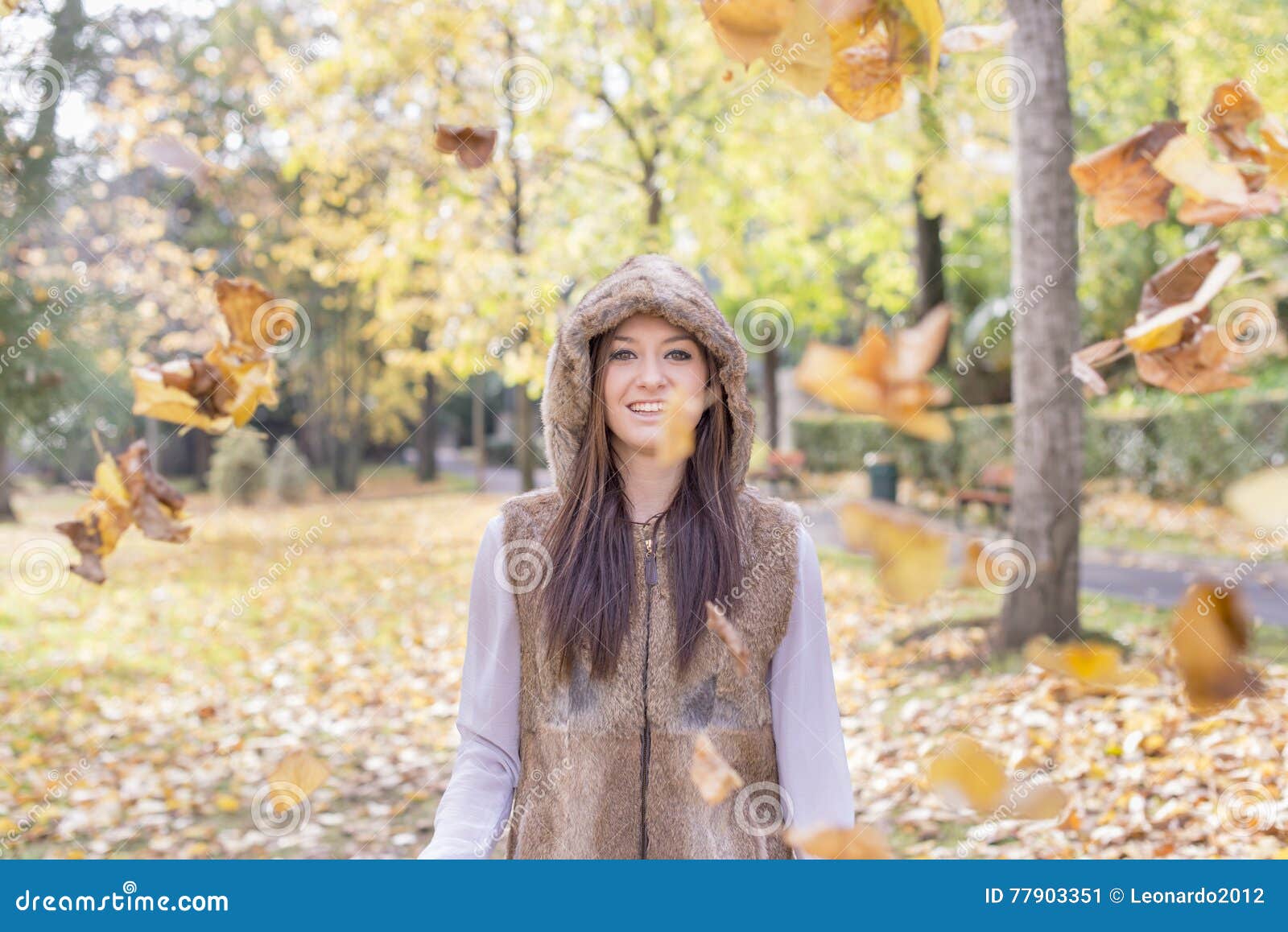 smiling girl with autumn leaves in the park.