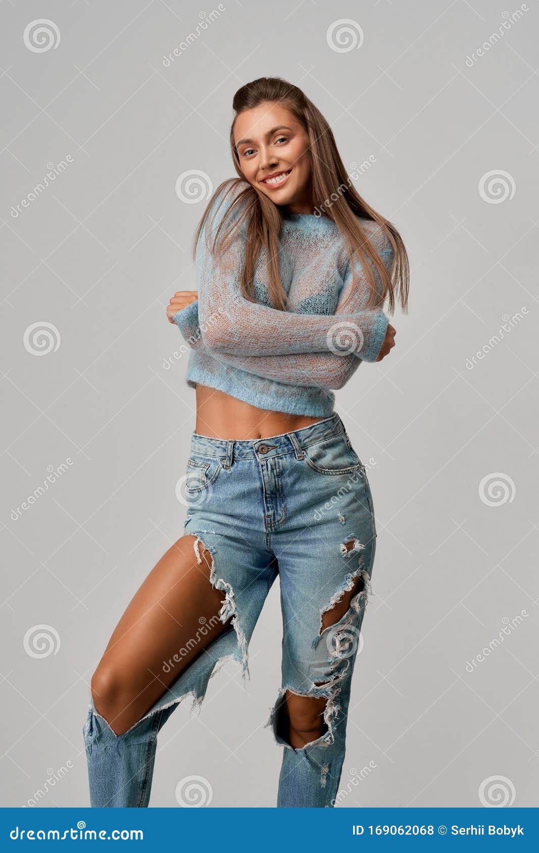 Smiling Girl Hugging Herself in Short Top, Ripped Jeans. Stock Photo of sunburnt, cheerful: 169062068