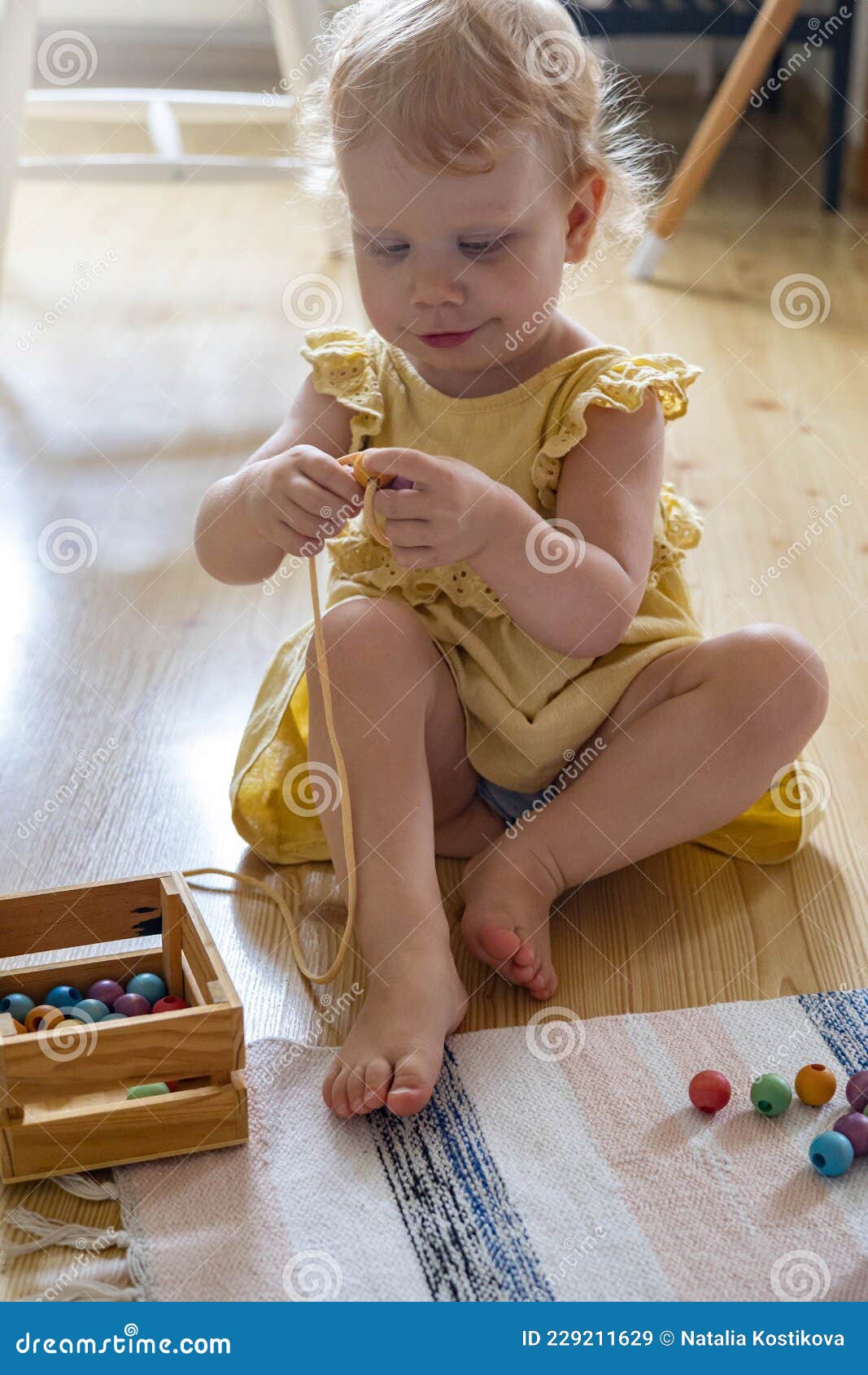 smiling girl playing wooden removable beads for development of fine motor skills maria montessori materials