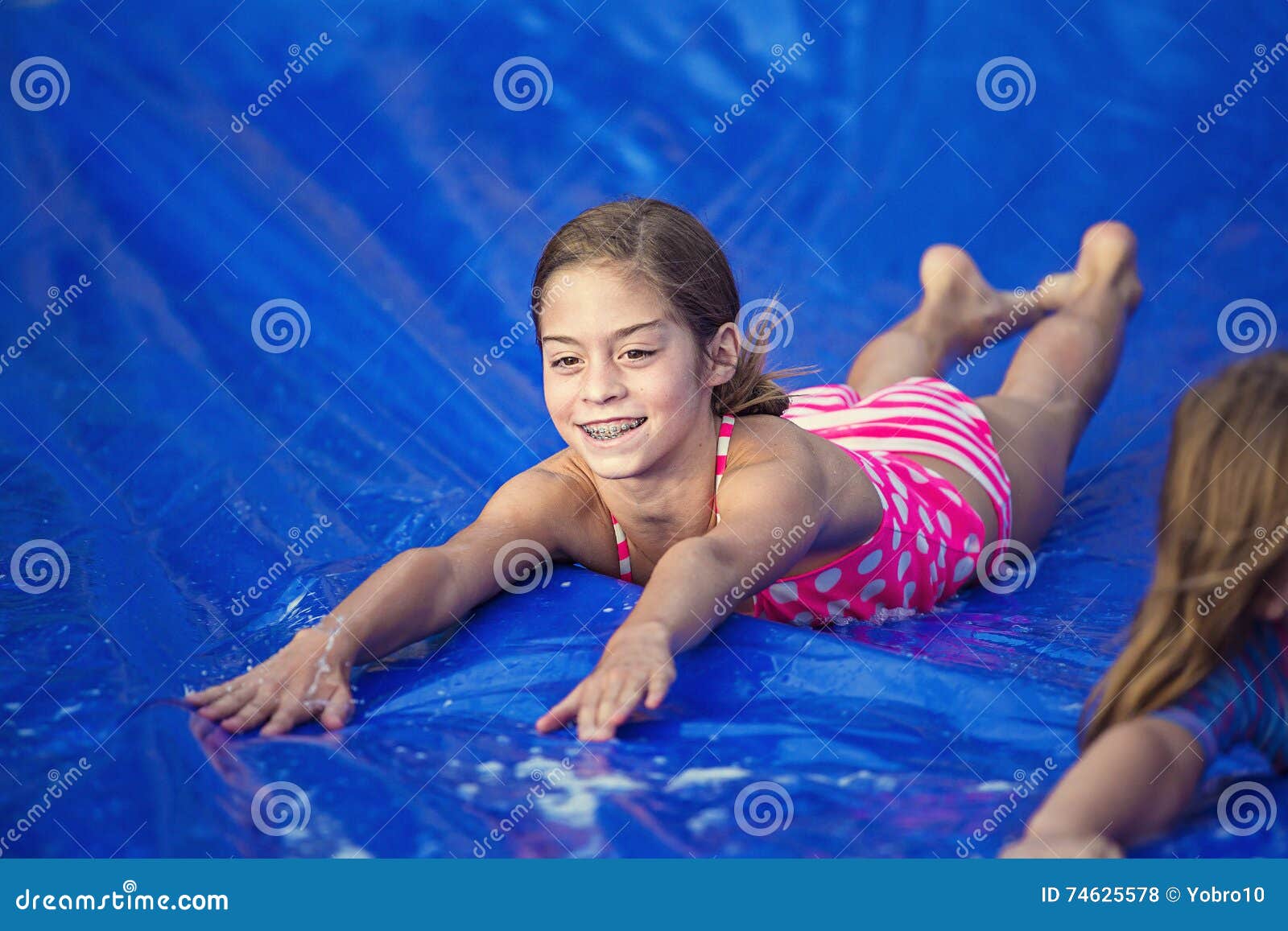 smiling girl sliding down an outdoor slip and slide