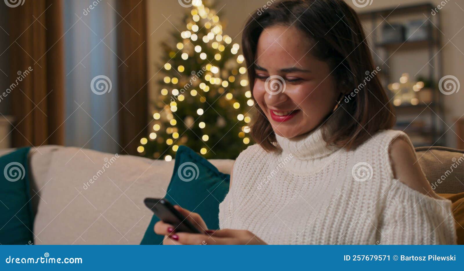 A Smiling Girl Spends Christmas Alone In Apartment The Woman Sits On Couch In Evening With