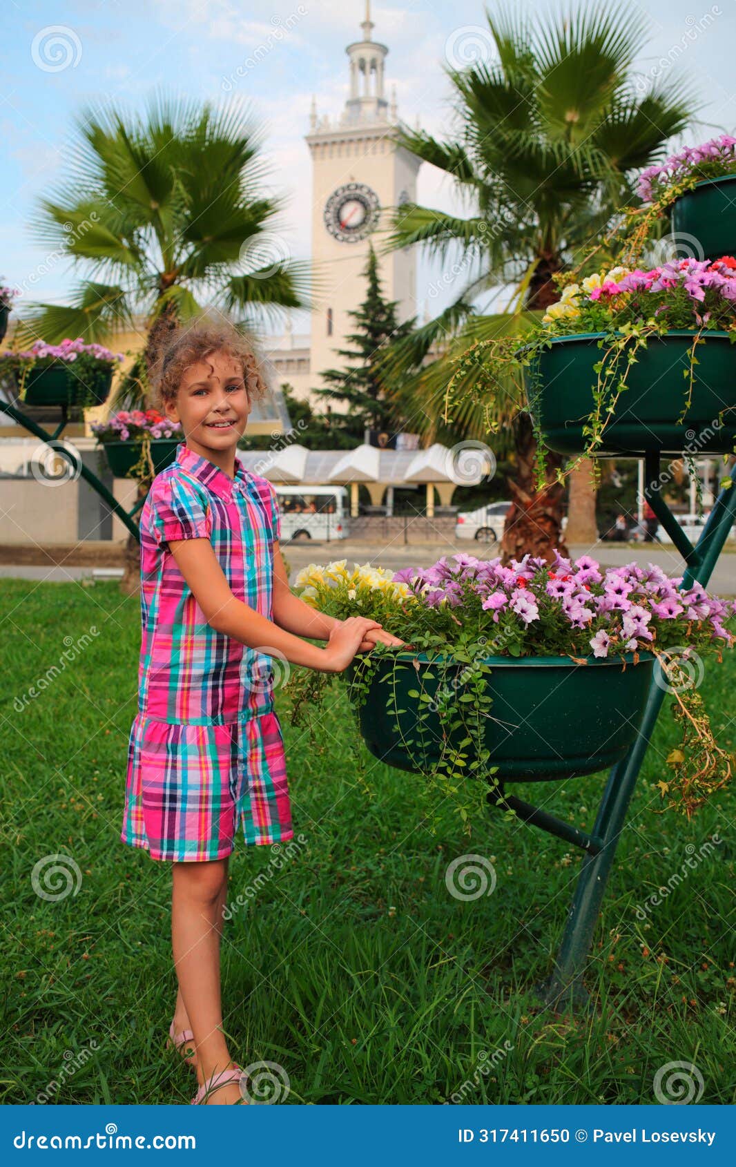 smiling girl standing near flowerpot with flowers