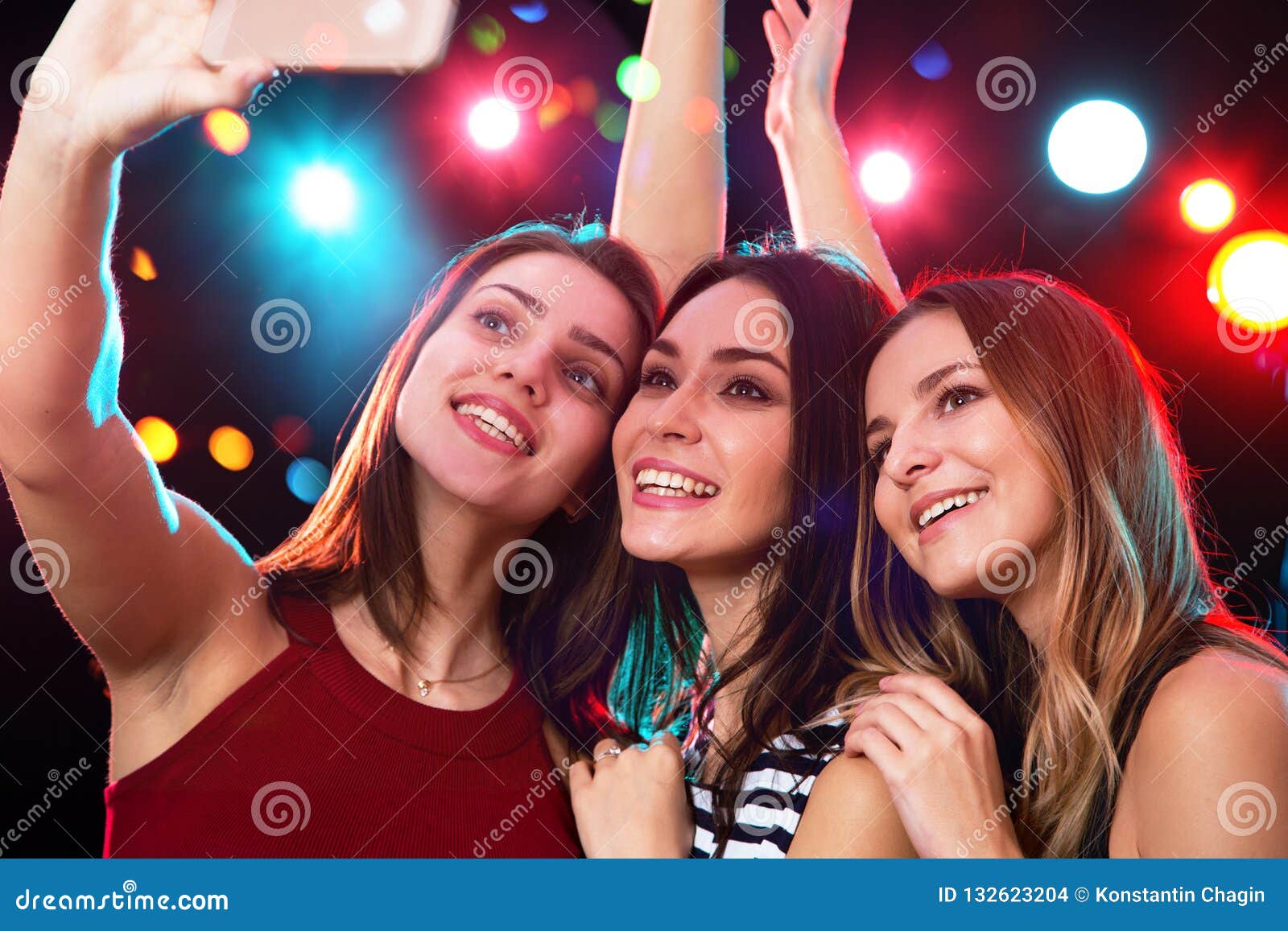 party, technology, nightlife and people concept - smiling friends with  smartphone taking selfie in club. Stock Photo