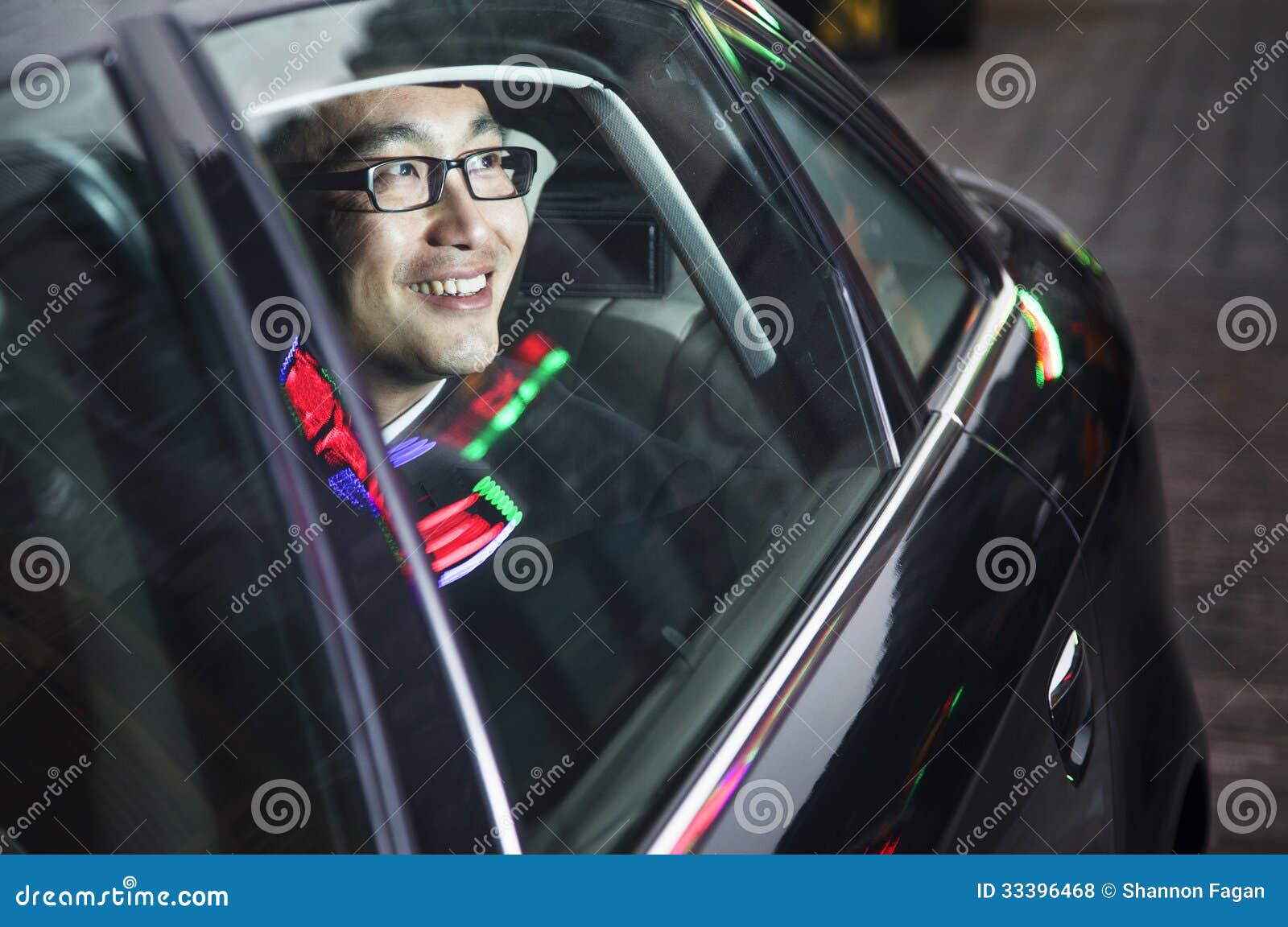 Smiling and Happy Businessman Looking through Car Window at the Night