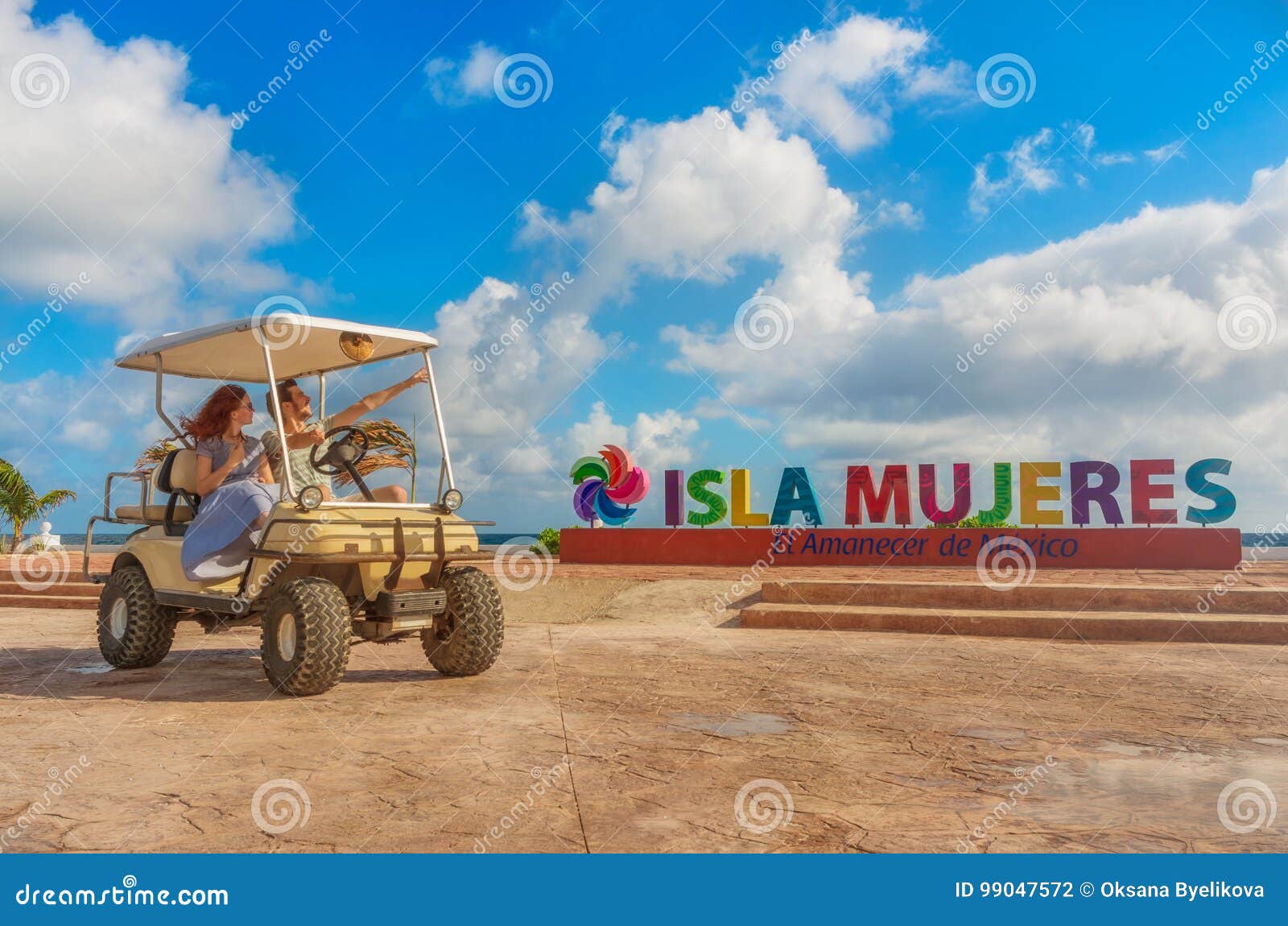 couple driving a golf cart at tropical beach on isla mujeres, mexico