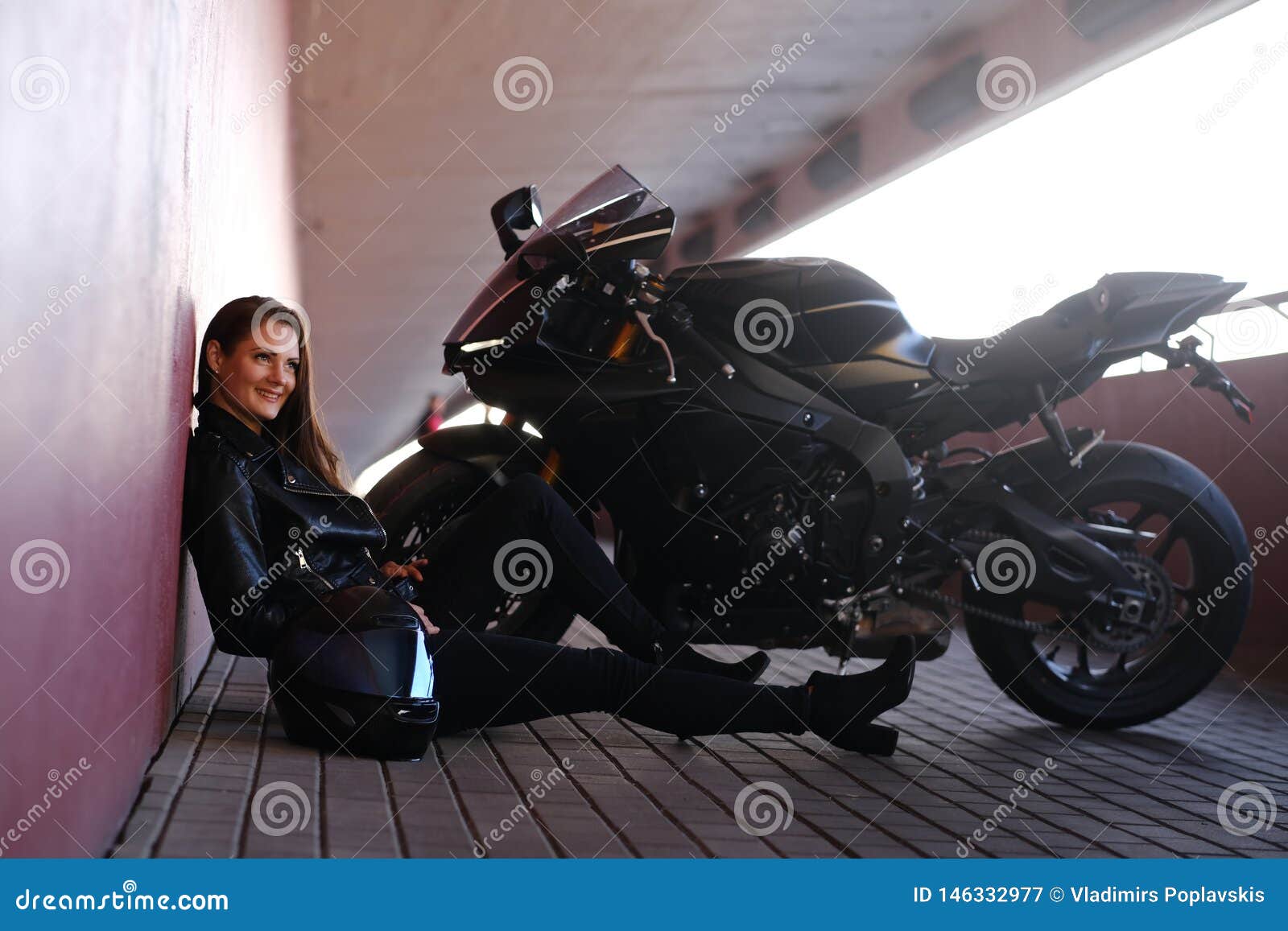 smiling happy girl is sitting in tunnel near her motobike