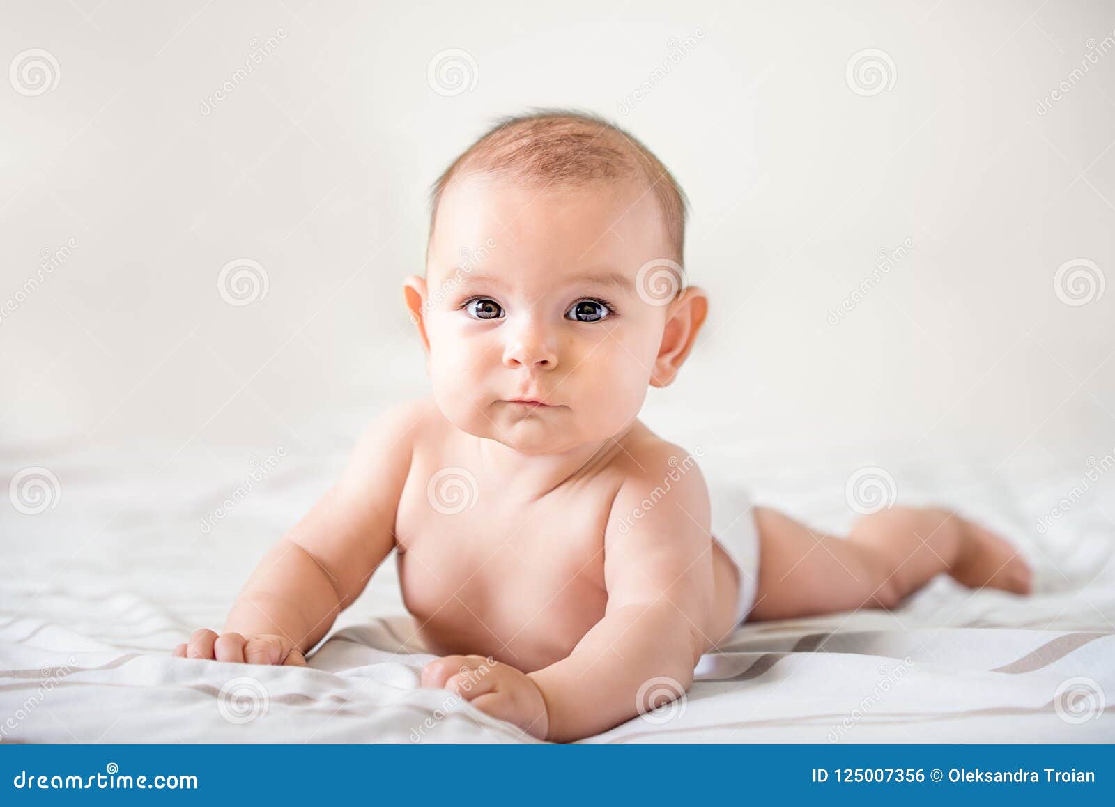 smiling happy newborn infant baby tummy time on bed bright airy copy space childhood