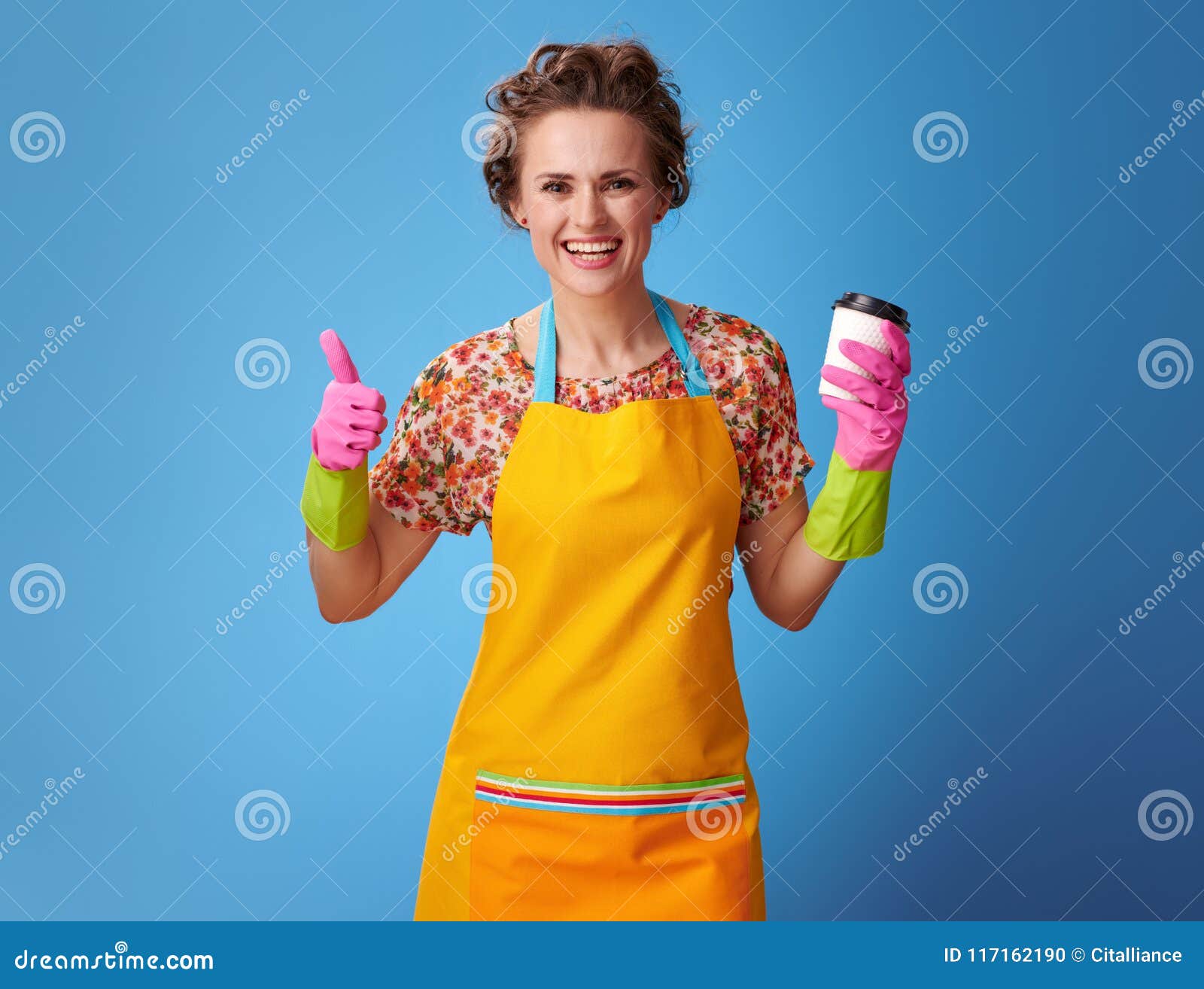 Smiling Housewife with Coffee Cup Showing Thumbs Up on Blue Stoc