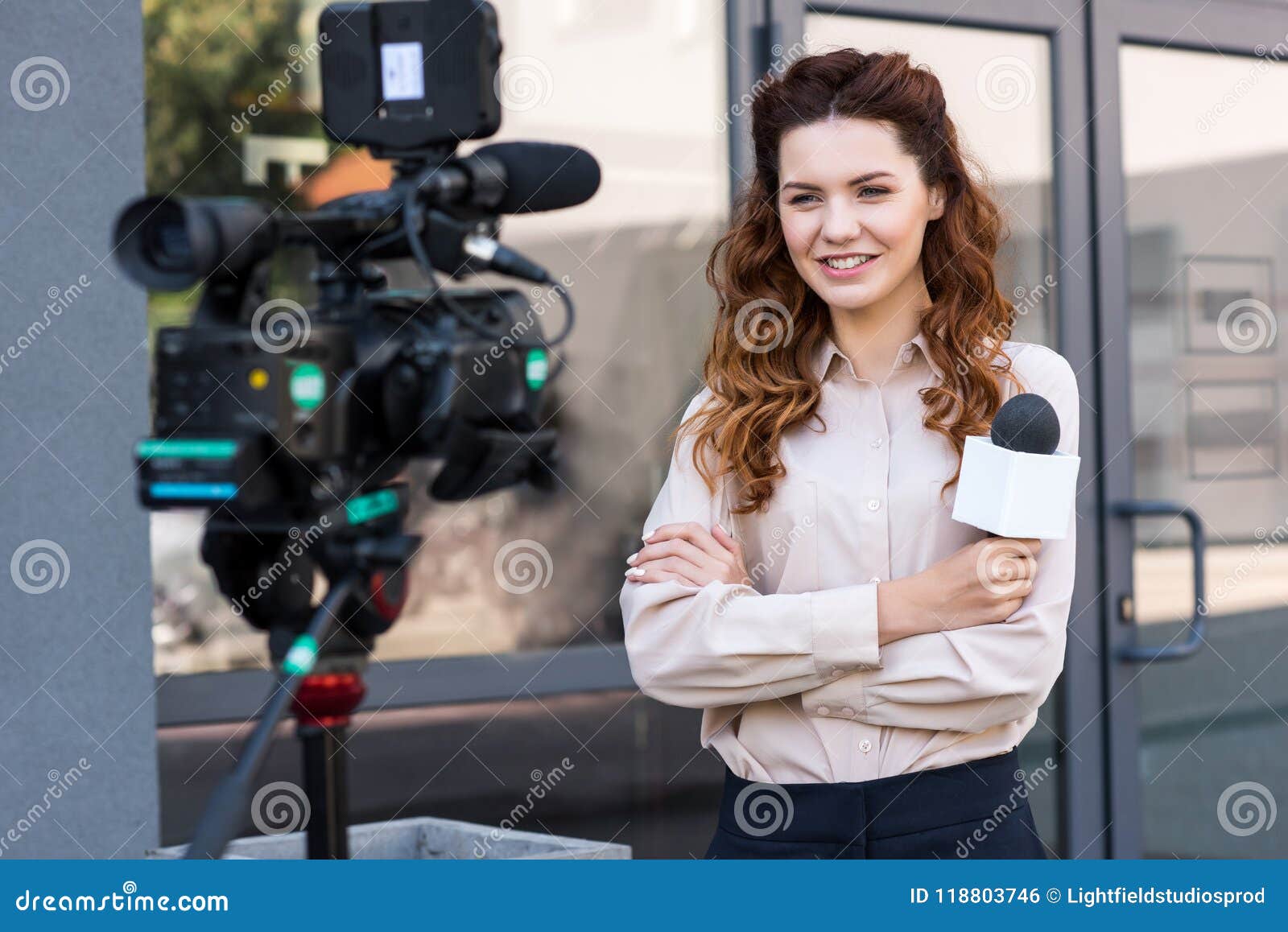 smiling journalist with microphone standing in front of digital