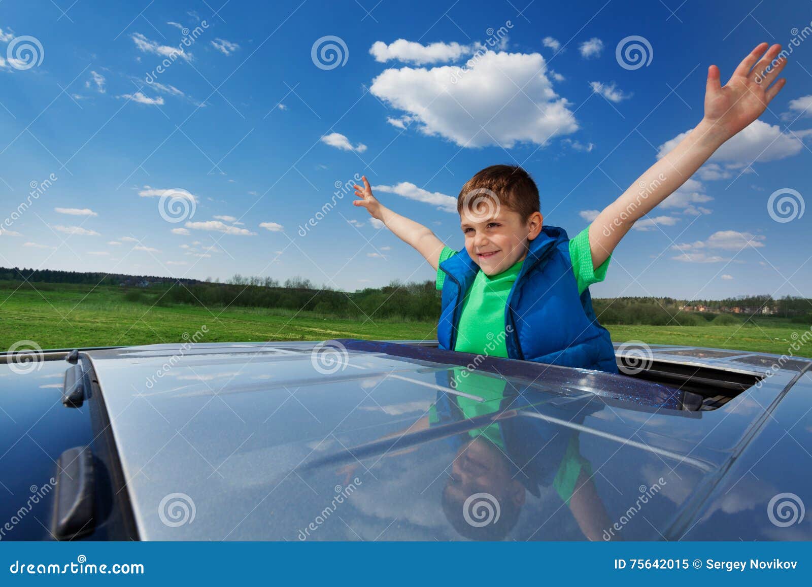 smiling kid boy enjoying freedom on sunroof of car