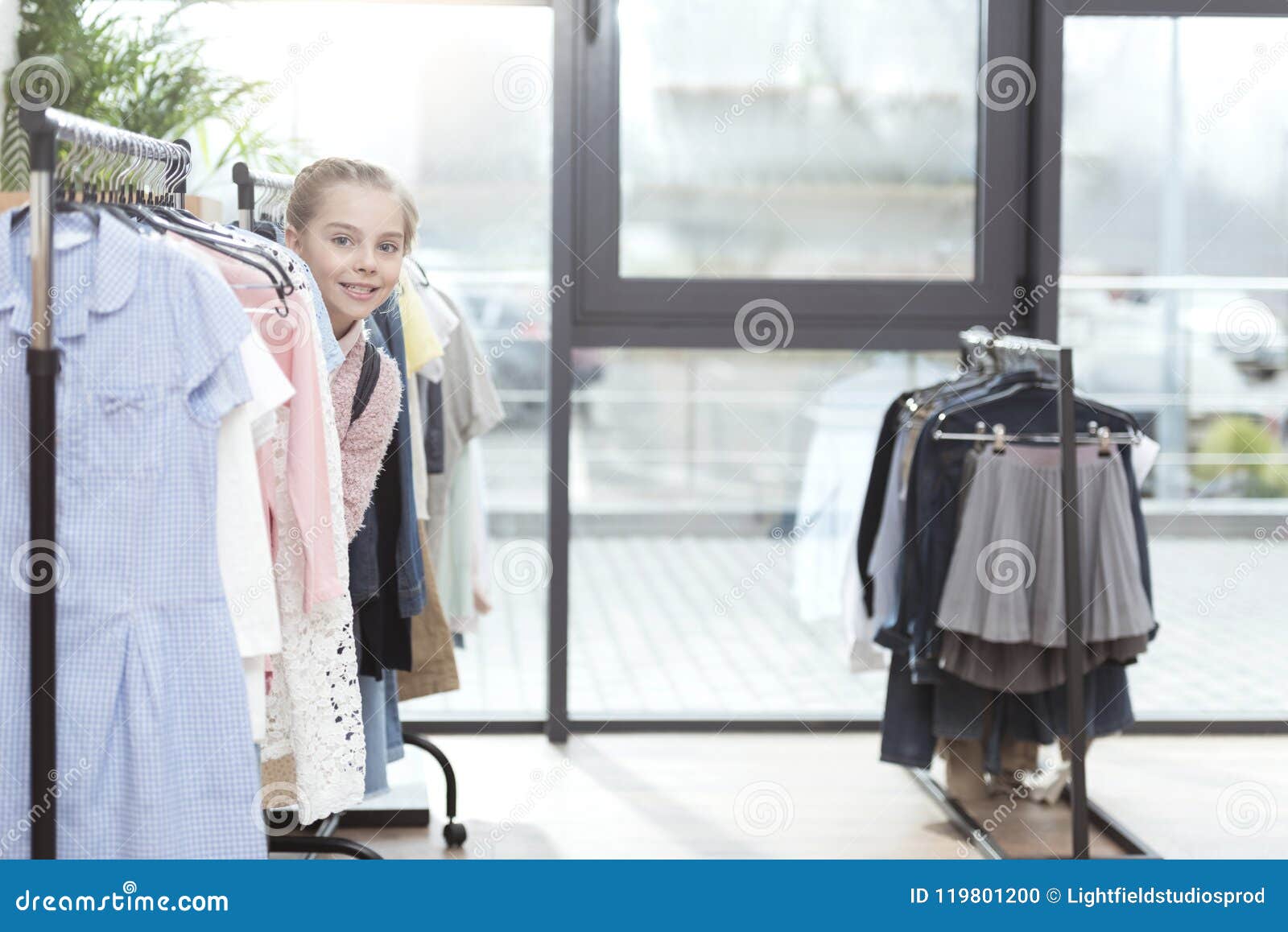 Smiling Kid Looking Out from Row of Clothes on Hanger Stock Photo ...