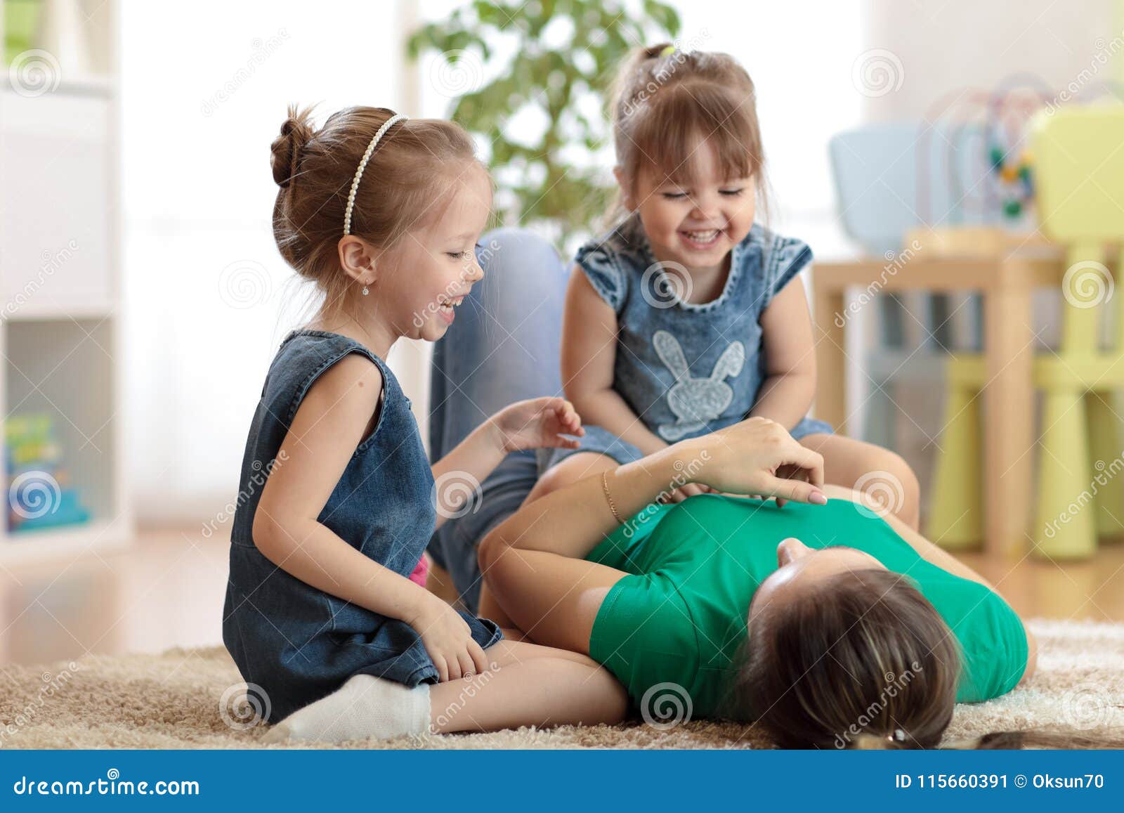 smiling kids and mom having a fun pastime on floor in children room at home