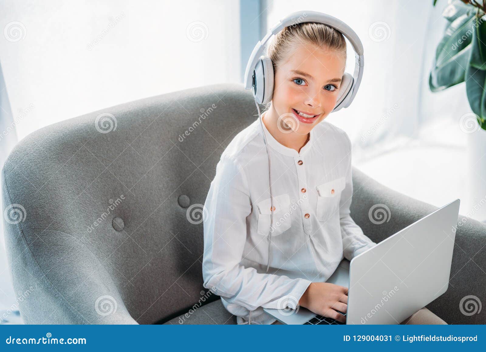 Smiling Little Child in Headphones Using Laptop while Sitting in ...