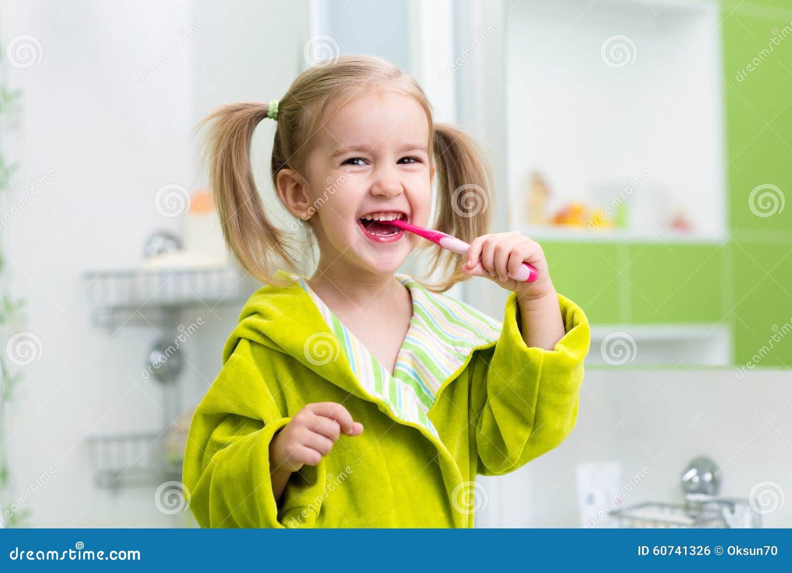 smiling little girl brushing teeth in bathroom