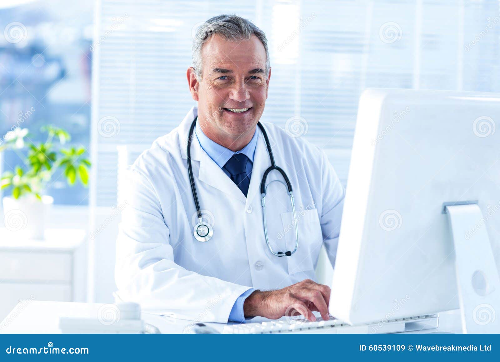 Smiling Male Doctor Using Computer in Clinic Stock Image - Image of ...