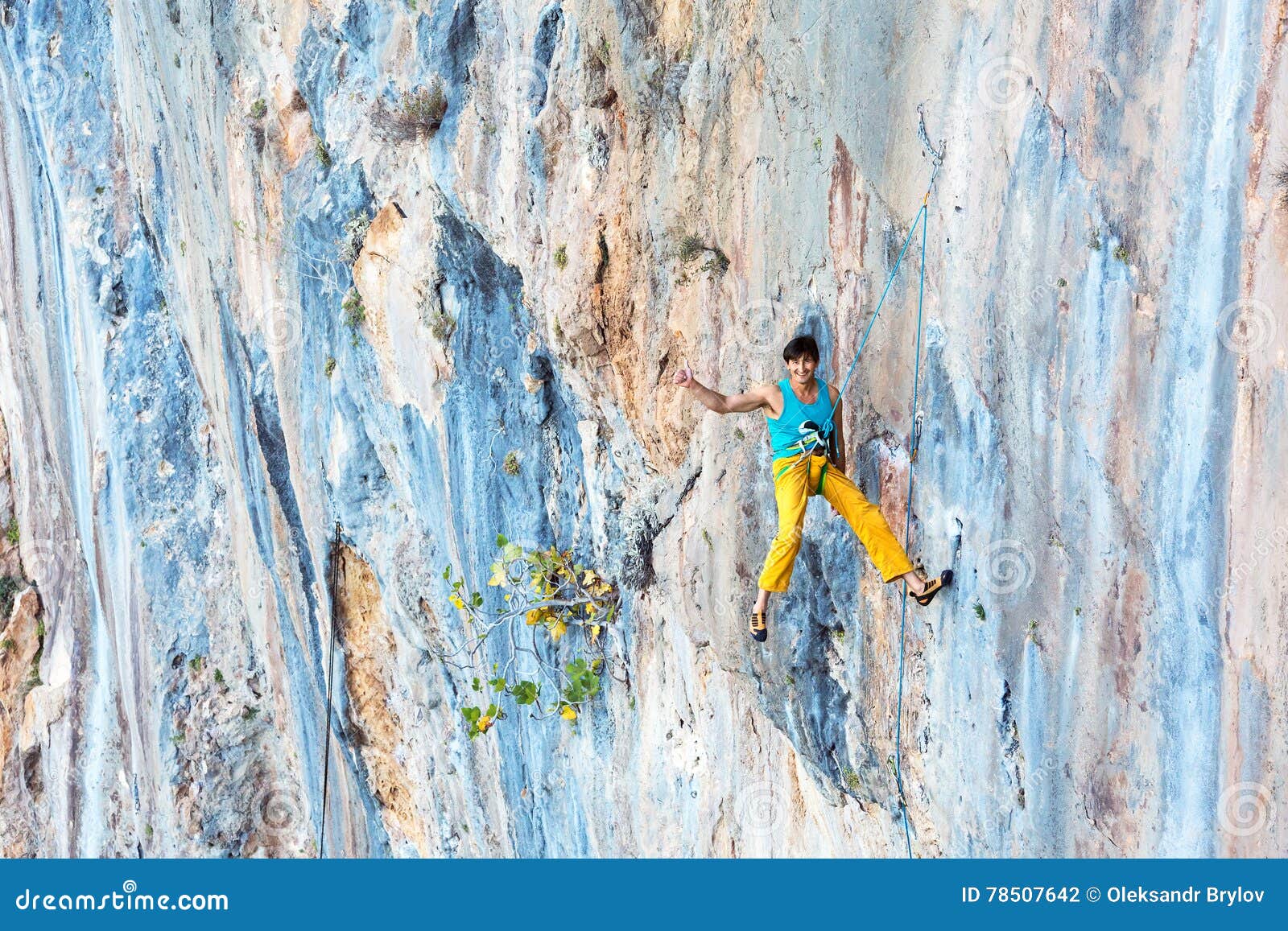 smiling male rock climber descending on rope with okey hand sign