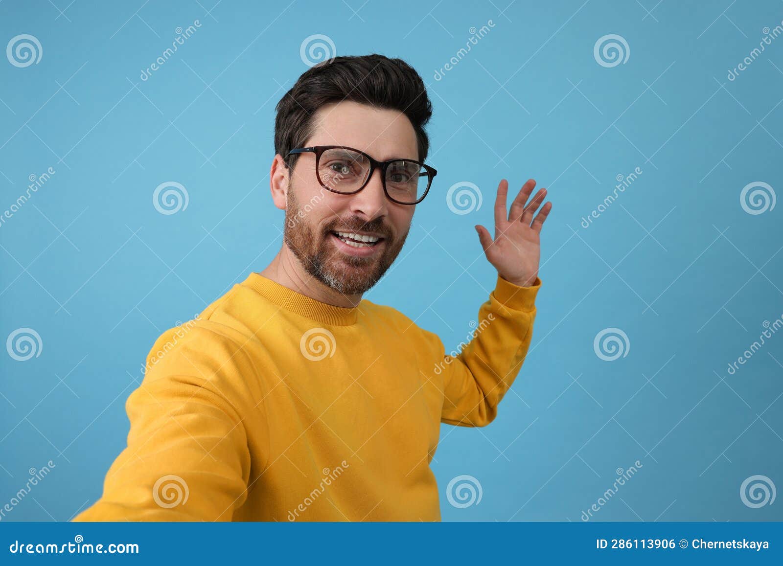 Smiling Man Taking Selfie on Light Blue Background Stock Photo Image